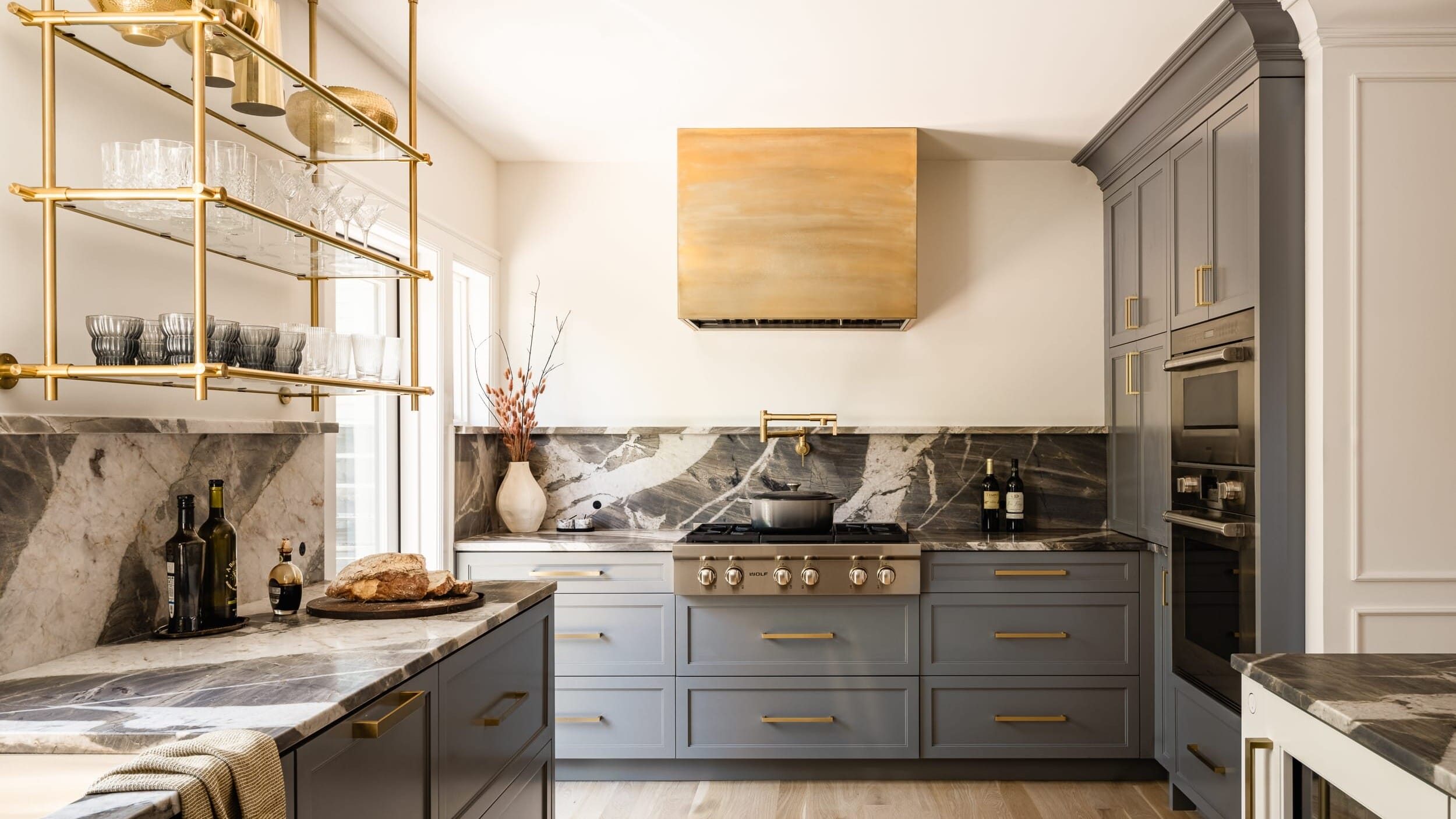 A gray and gold kitchen with marble counter tops.