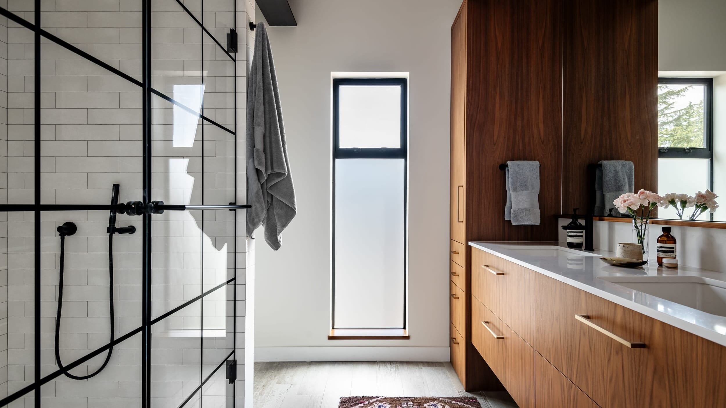 A modern bathroom with wooden cabinets and a glass shower.