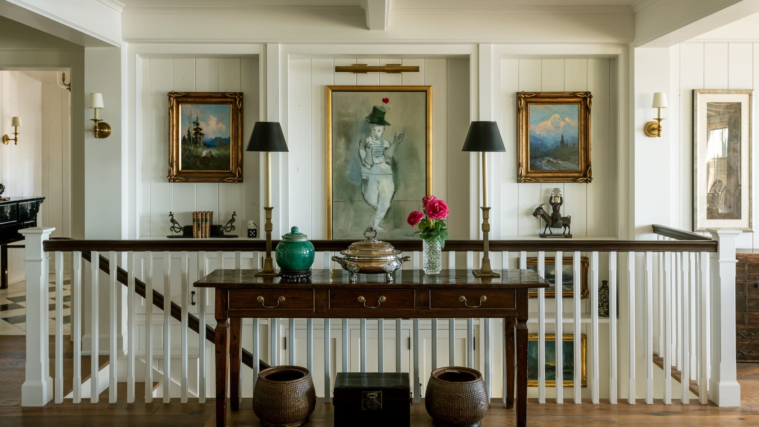 An entryway with a table and paintings.