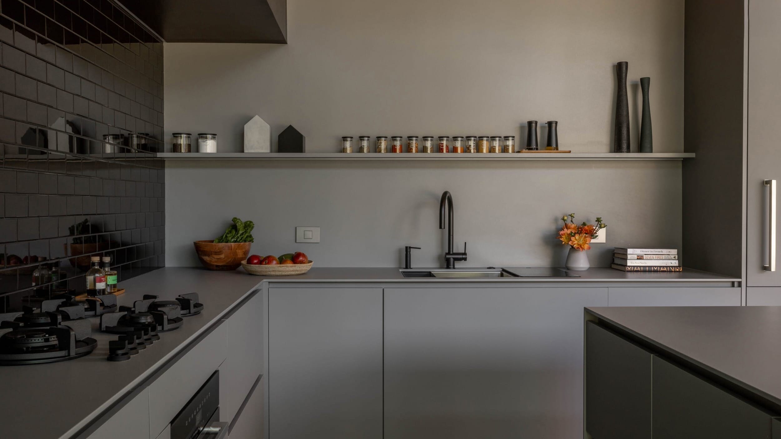 A modern kitchen with black and grey tiled walls.