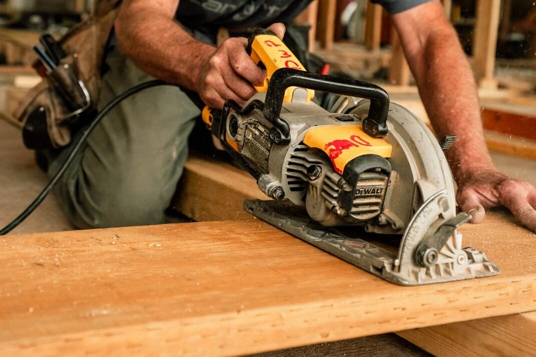 A Home Builder in Seattle is skillfully using a circular saw on wood.