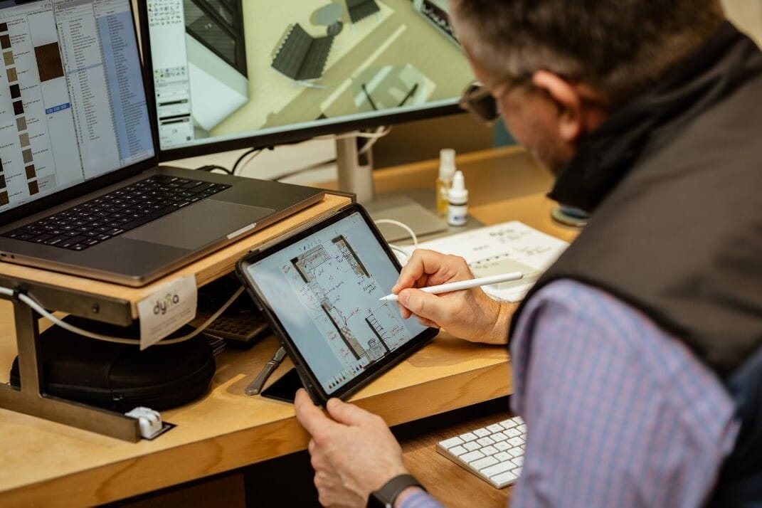 A man using an iPad at a desk while working with Dyna Builders.