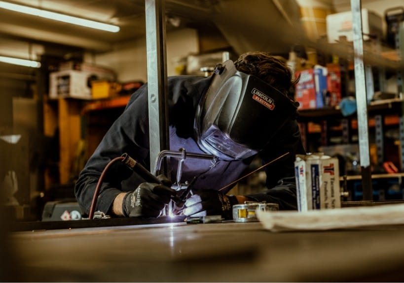 A skilled welder diligently working on a piece of metal at Dyna Seattle Home Builders.