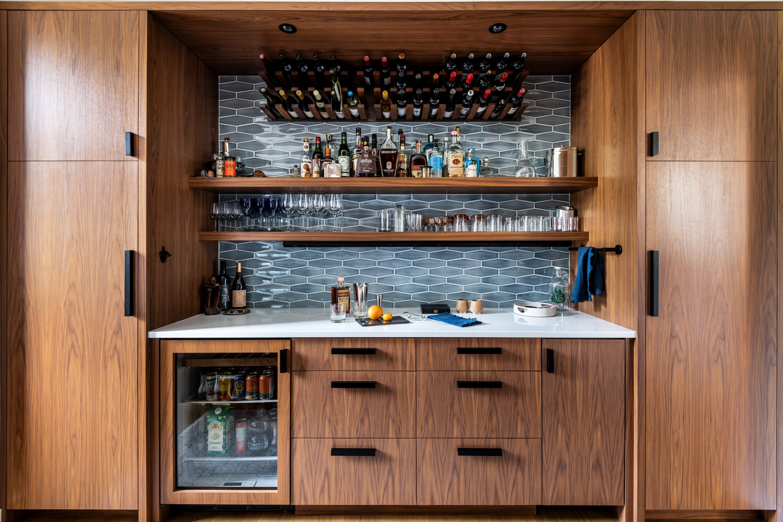 A home bar with wooden cabinets and a refrigerator.