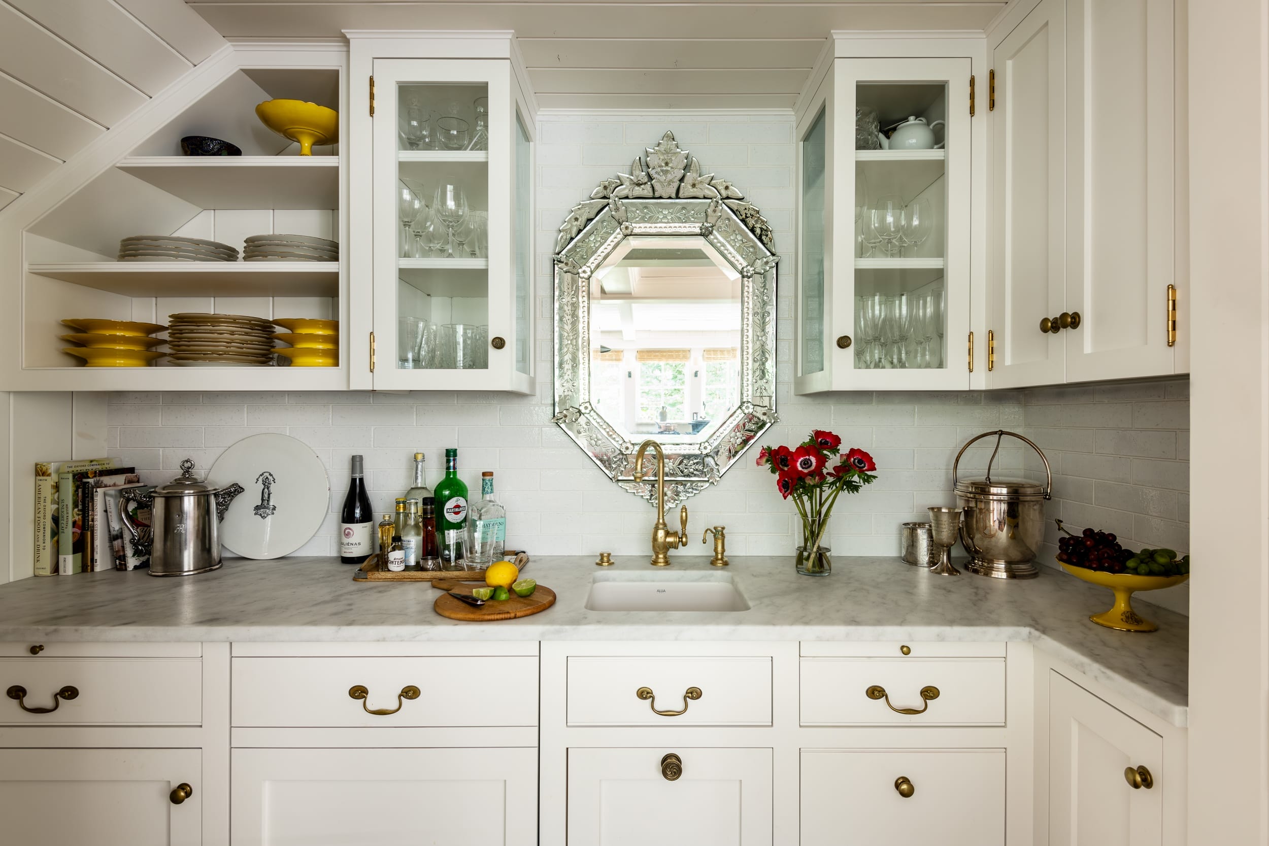 A kitchen with white cabinets and a mirror.