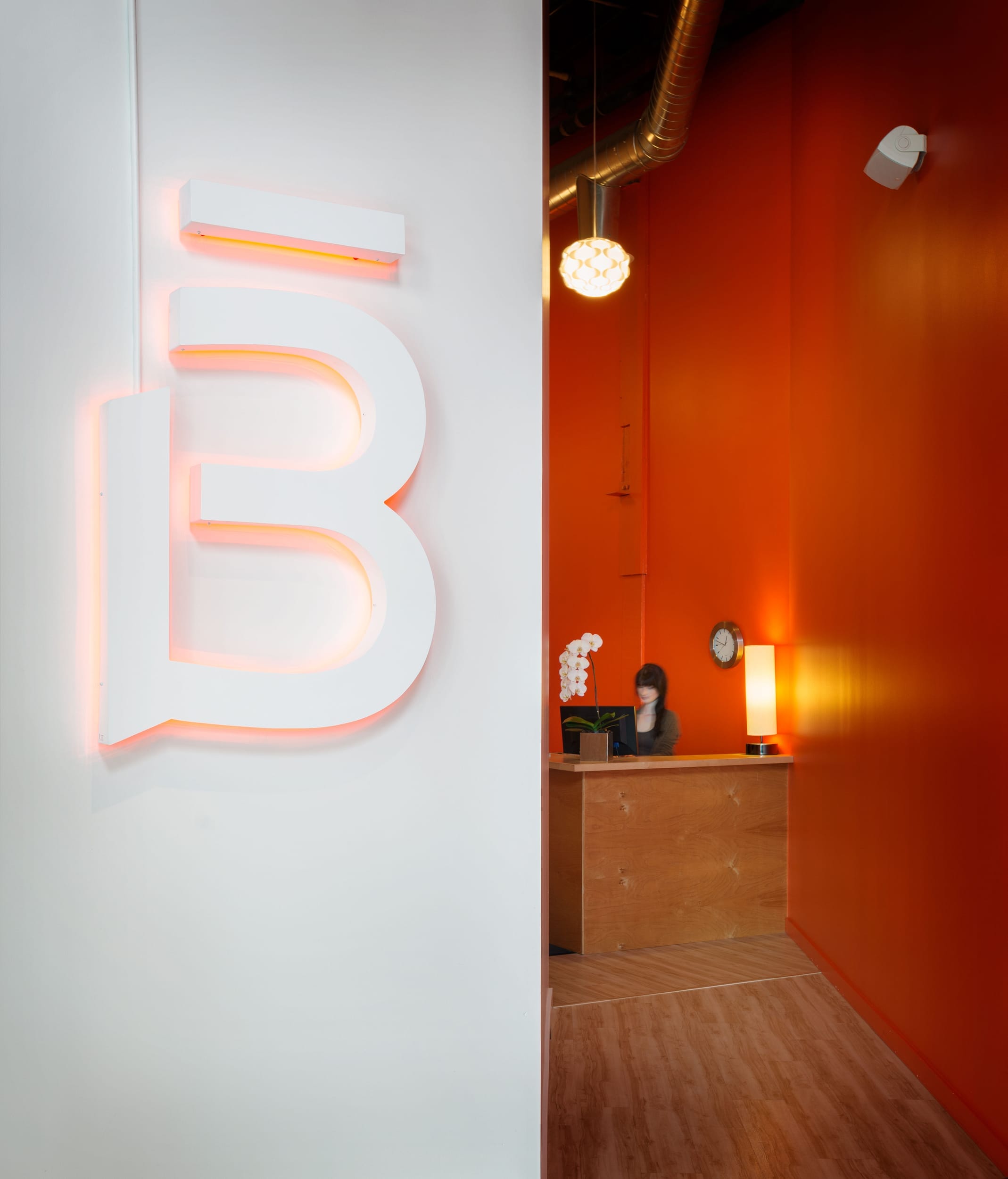 A bright orange office with the letter b on the wall.