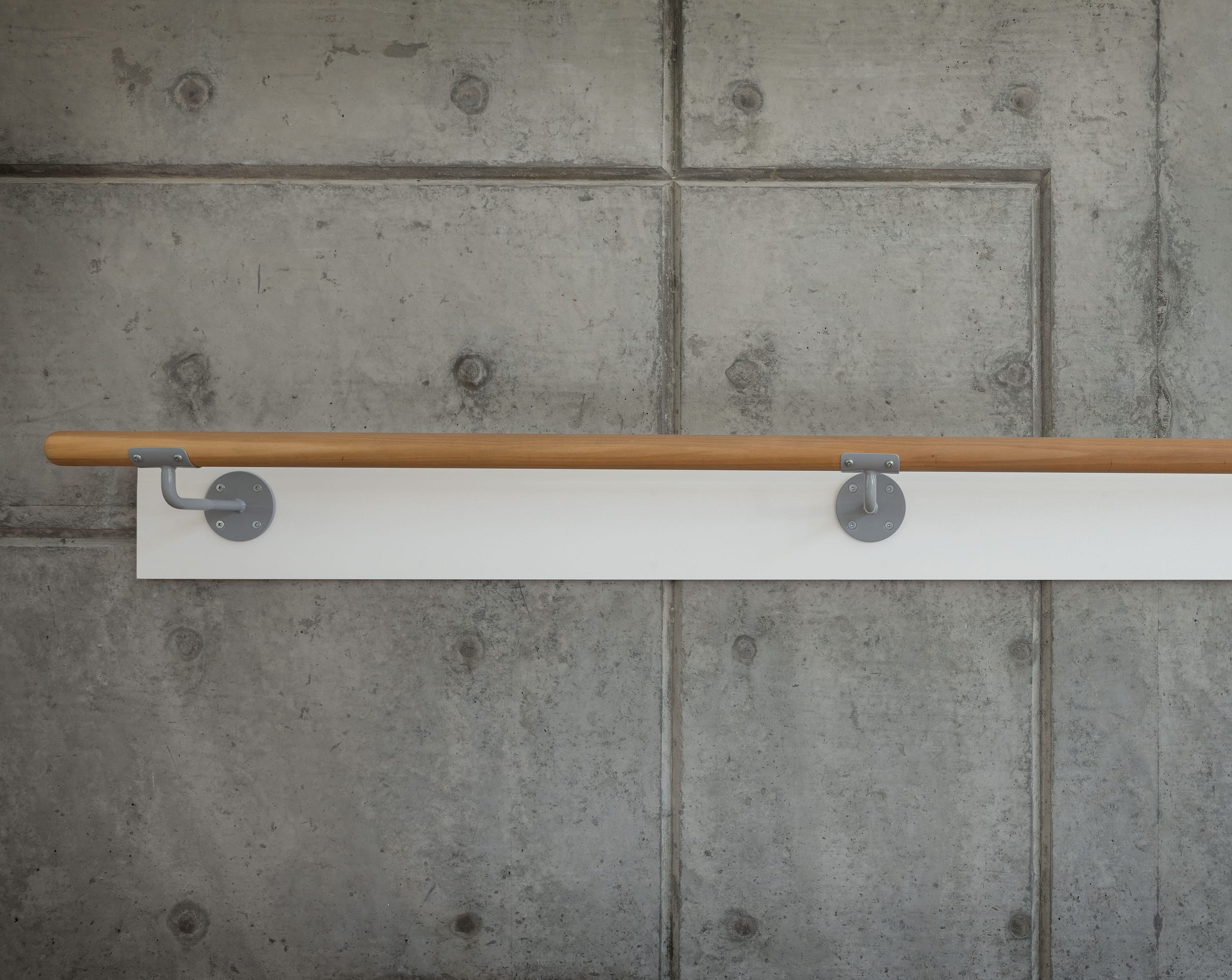A wooden rail hanging on a concrete wall.