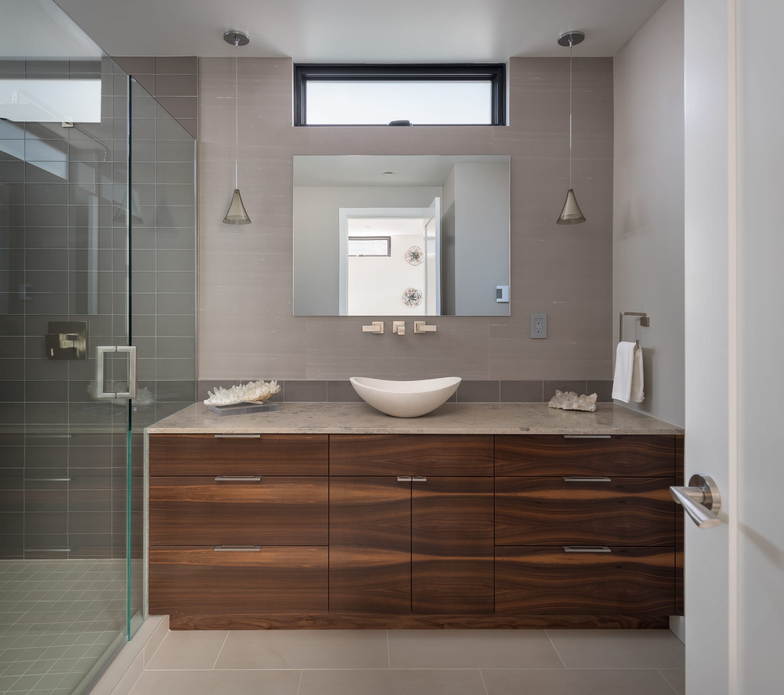 A modern bathroom with wooden cabinets and a glass shower, suitable for a modern home.