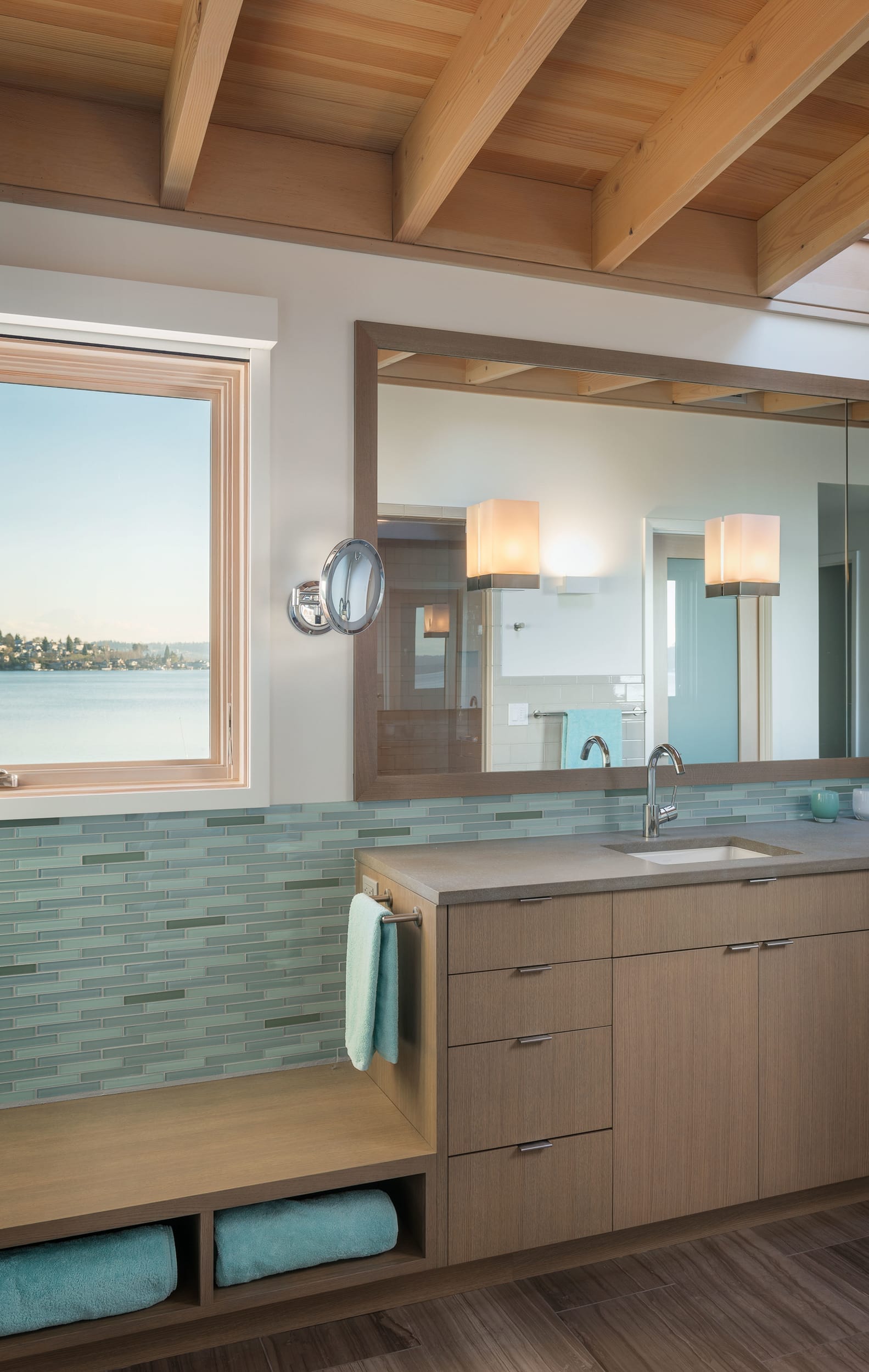 A bathroom with a sink and a window overlooking the water.