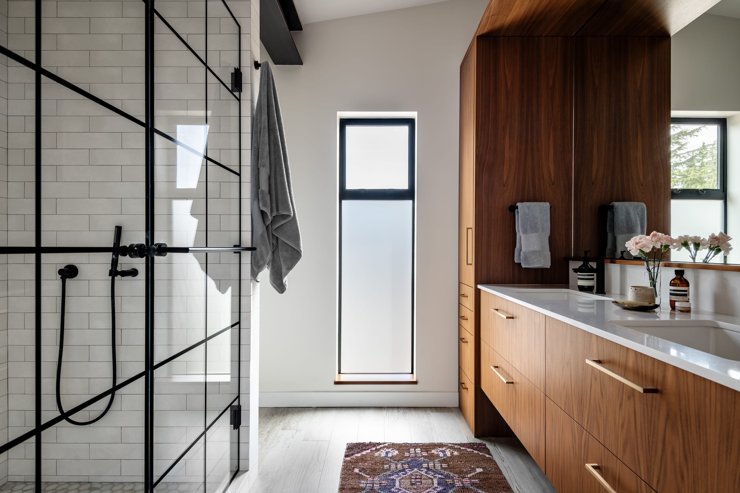 A modern bathroom with wooden cabinets and a glass shower.