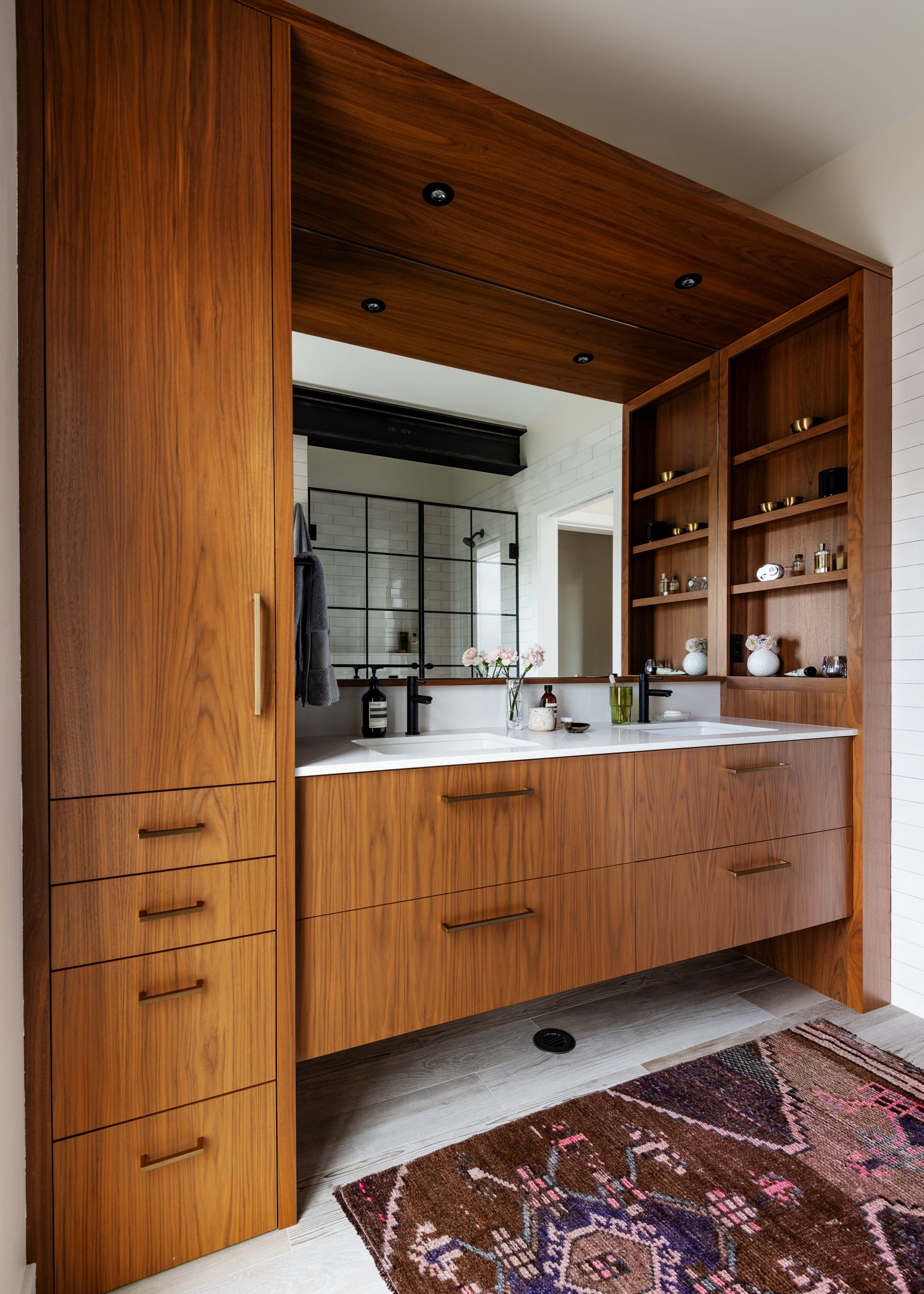 A bathroom with wooden cabinets and a rug.