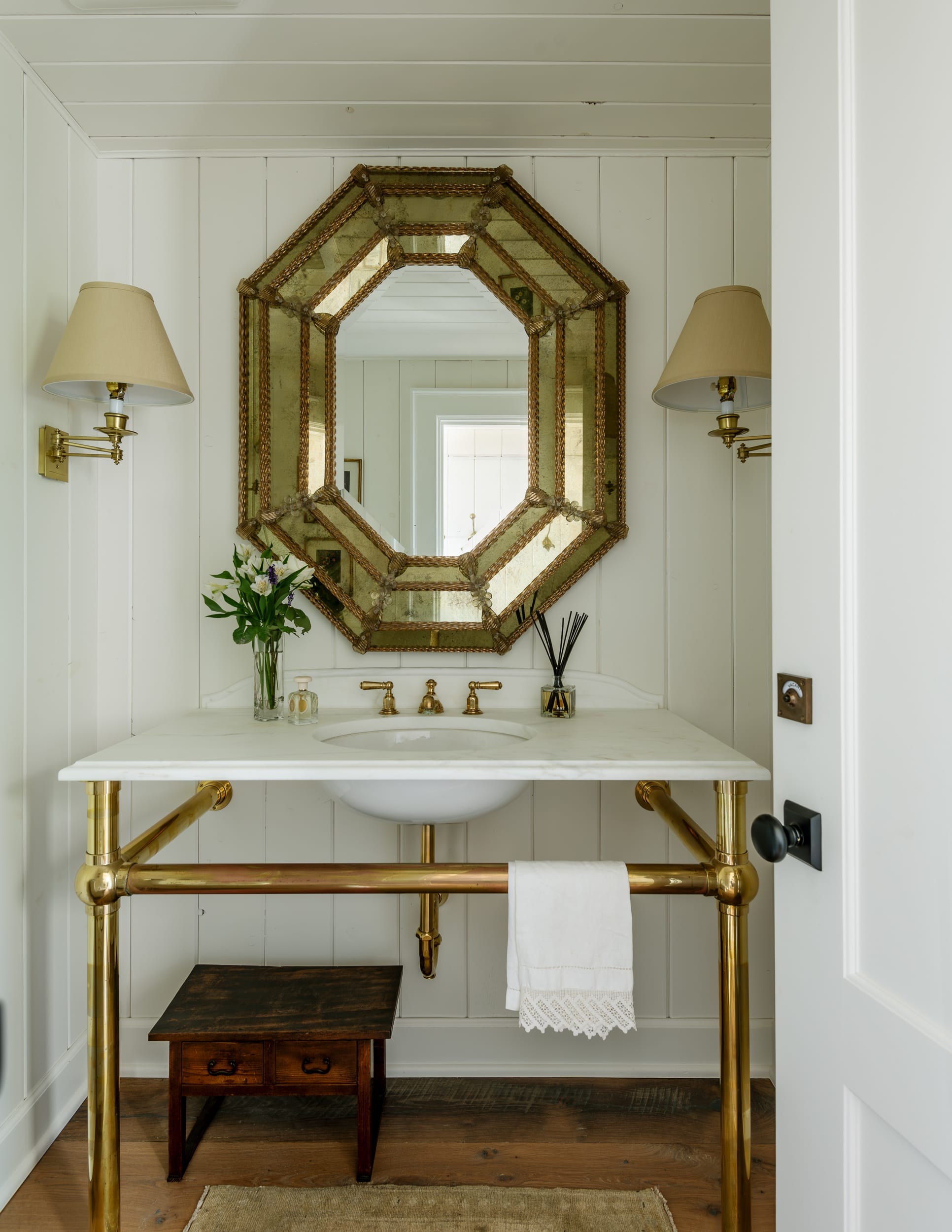 A white bathroom with a gold mirror.