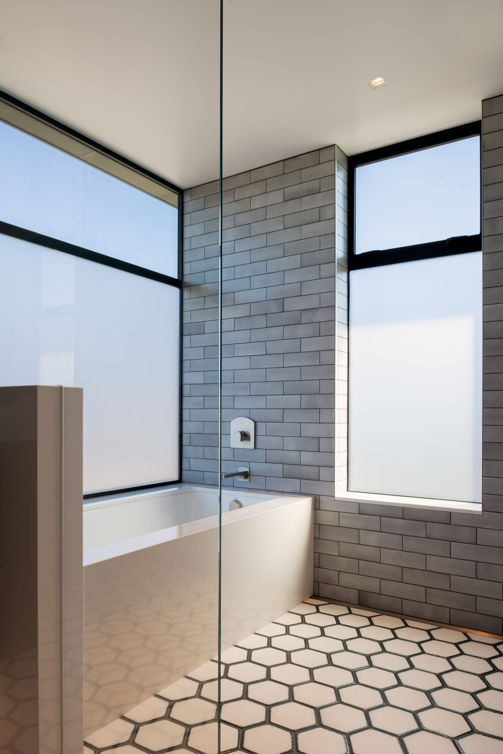 A bathroom with a glass shower and tiled floor.