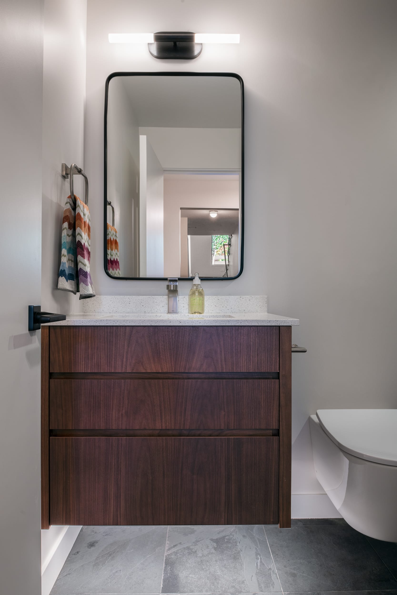 A modern bathroom with a wooden vanity and mirror.