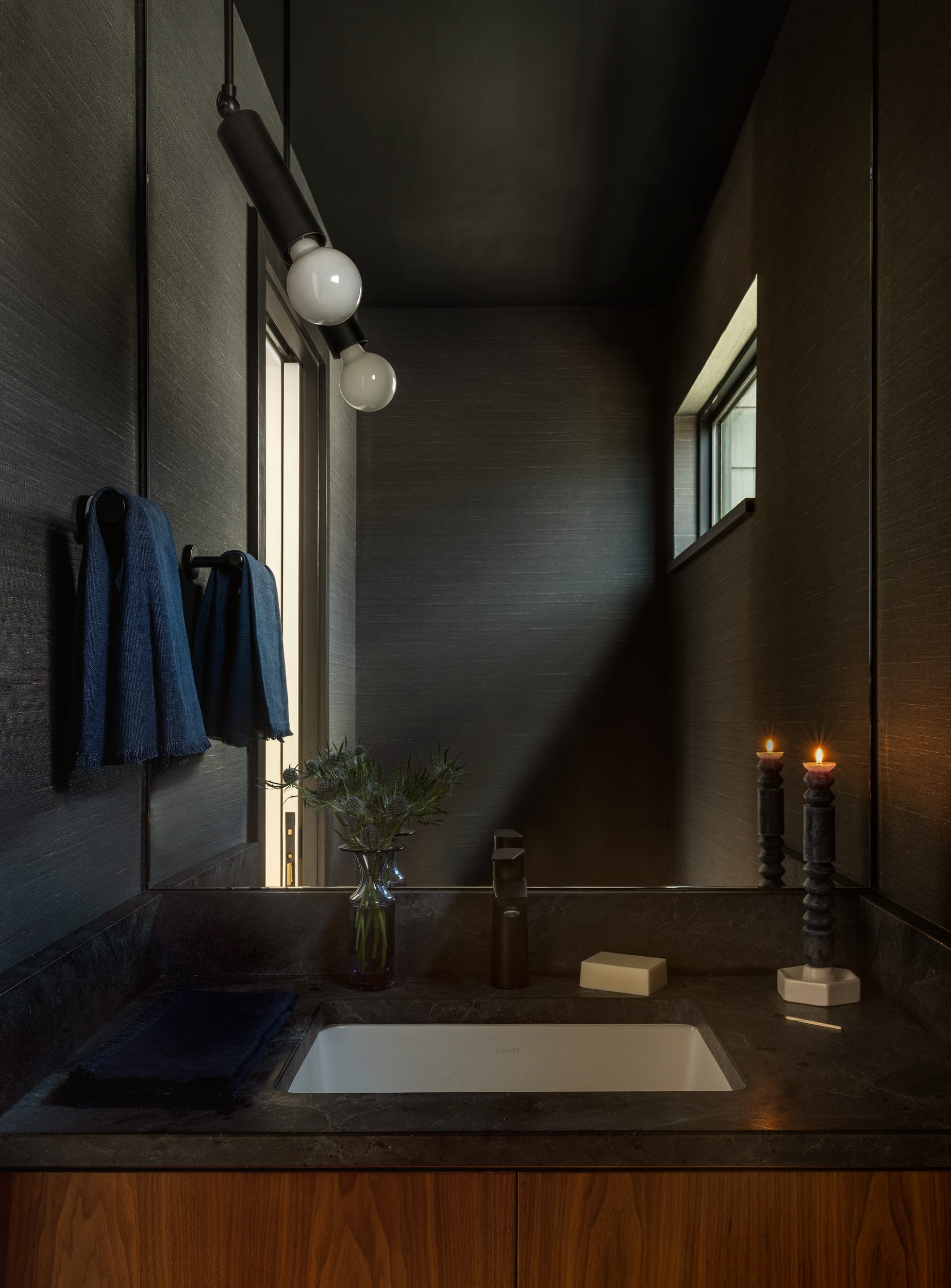 A bathroom with black walls and a sink.