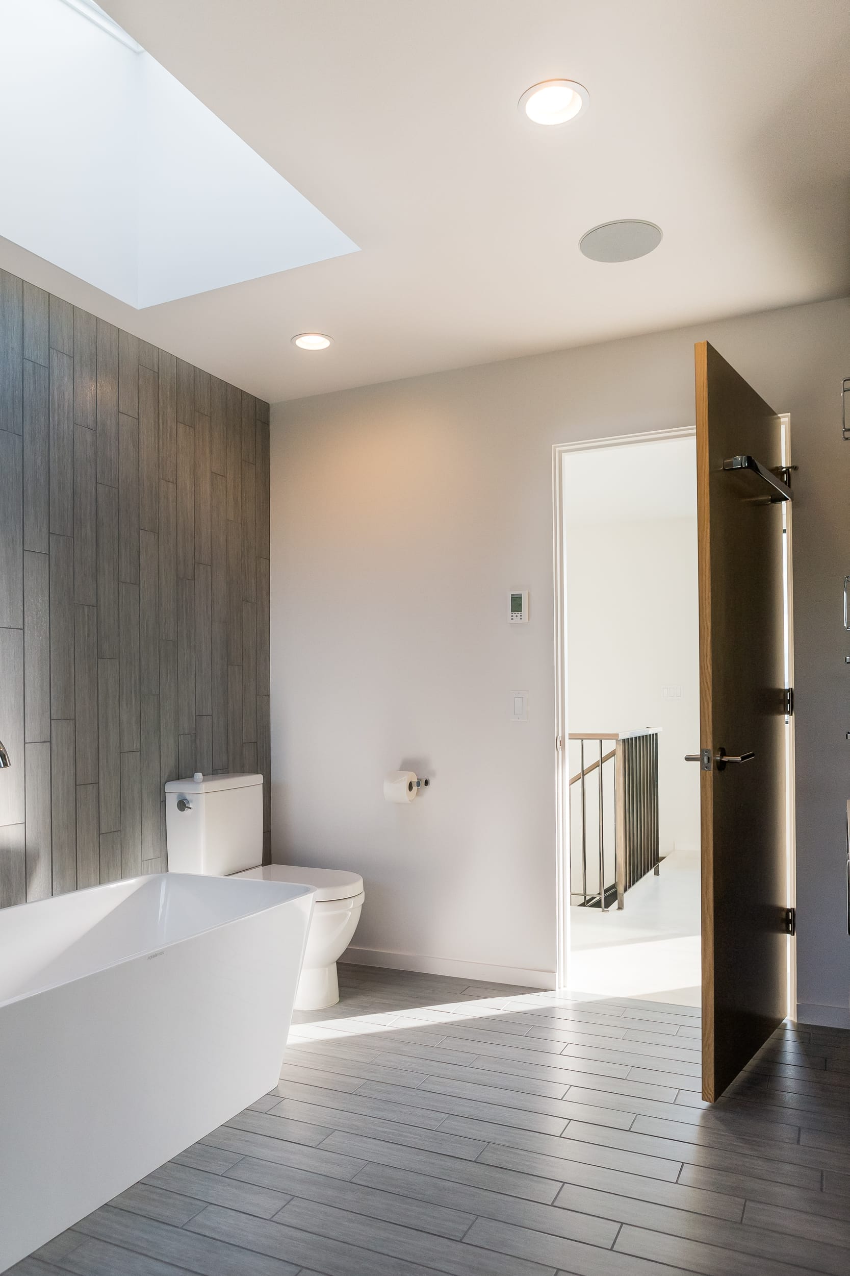 A modern bathroom with a skylight and wooden floors.