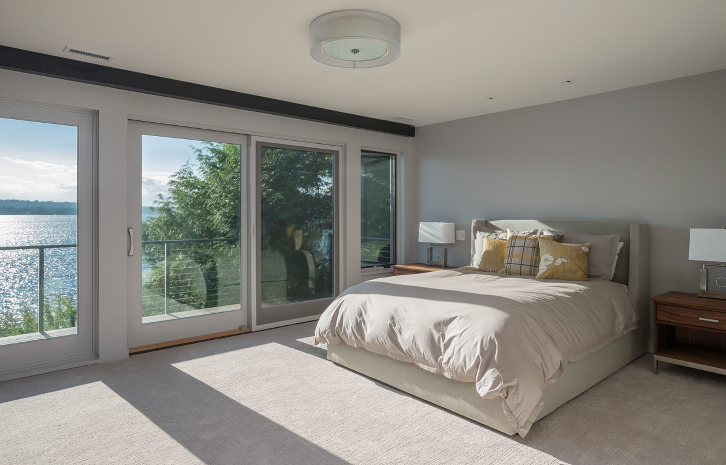 A bedroom with sliding glass doors and a view of the water.