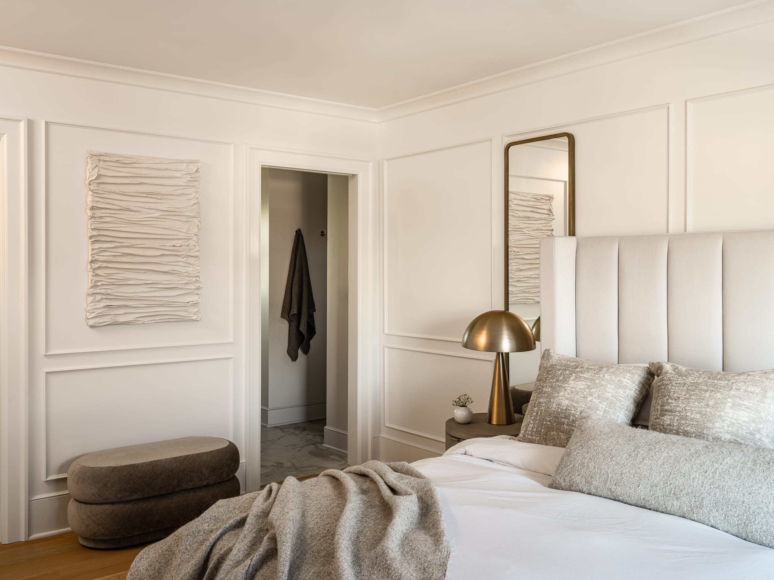 A bedroom with white walls and a white headboard.