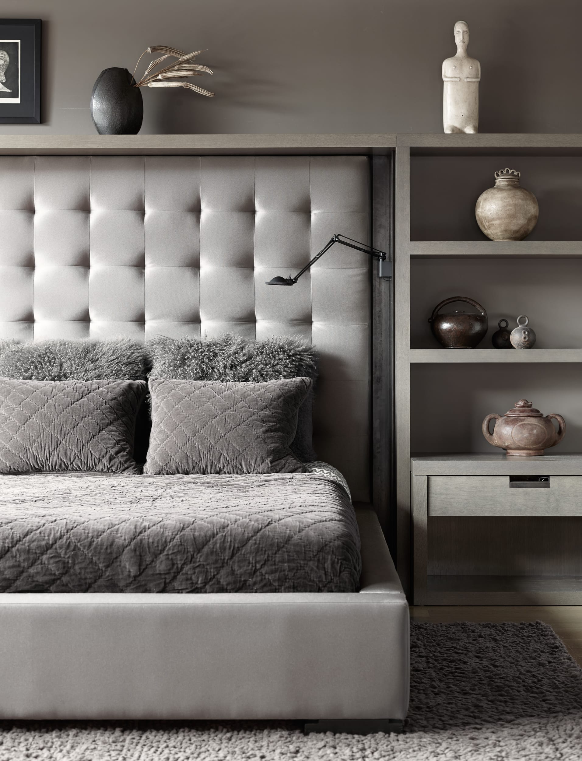 A modern bedroom with a grey headboard and dresser.