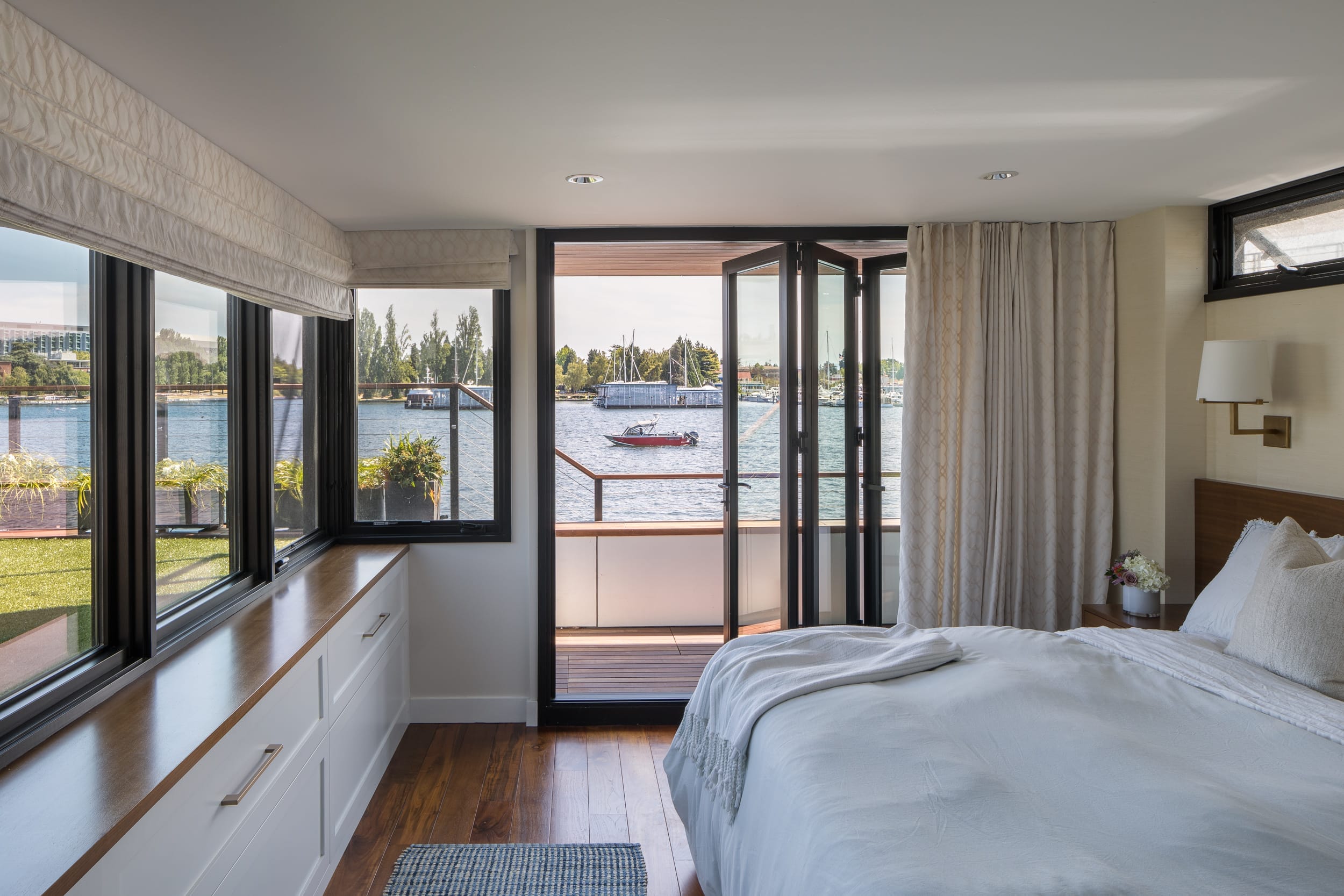 A modern bedroom with a large window overlooking the water in a floating home.