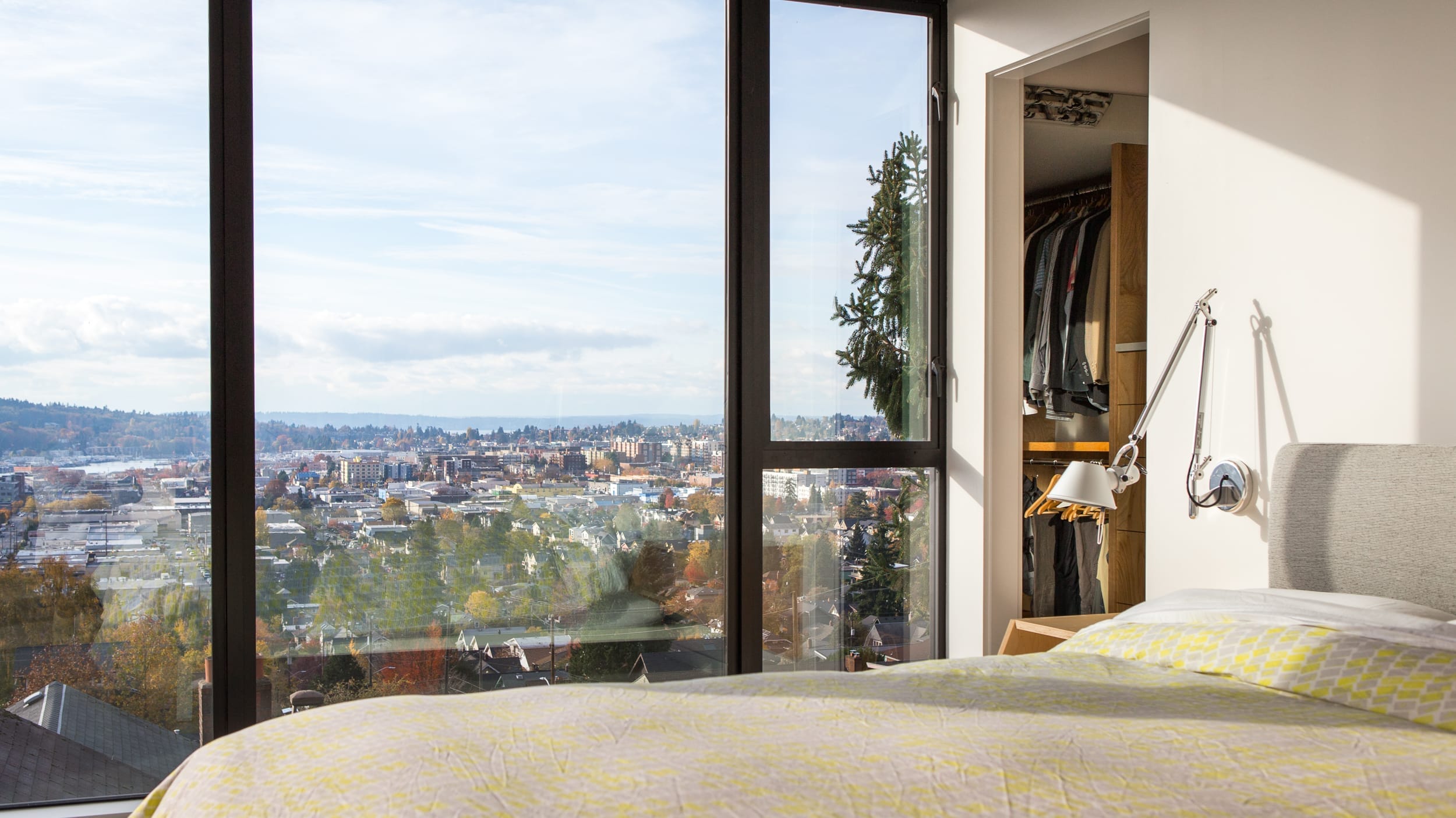 A bed in a bedroom with a view of a city.