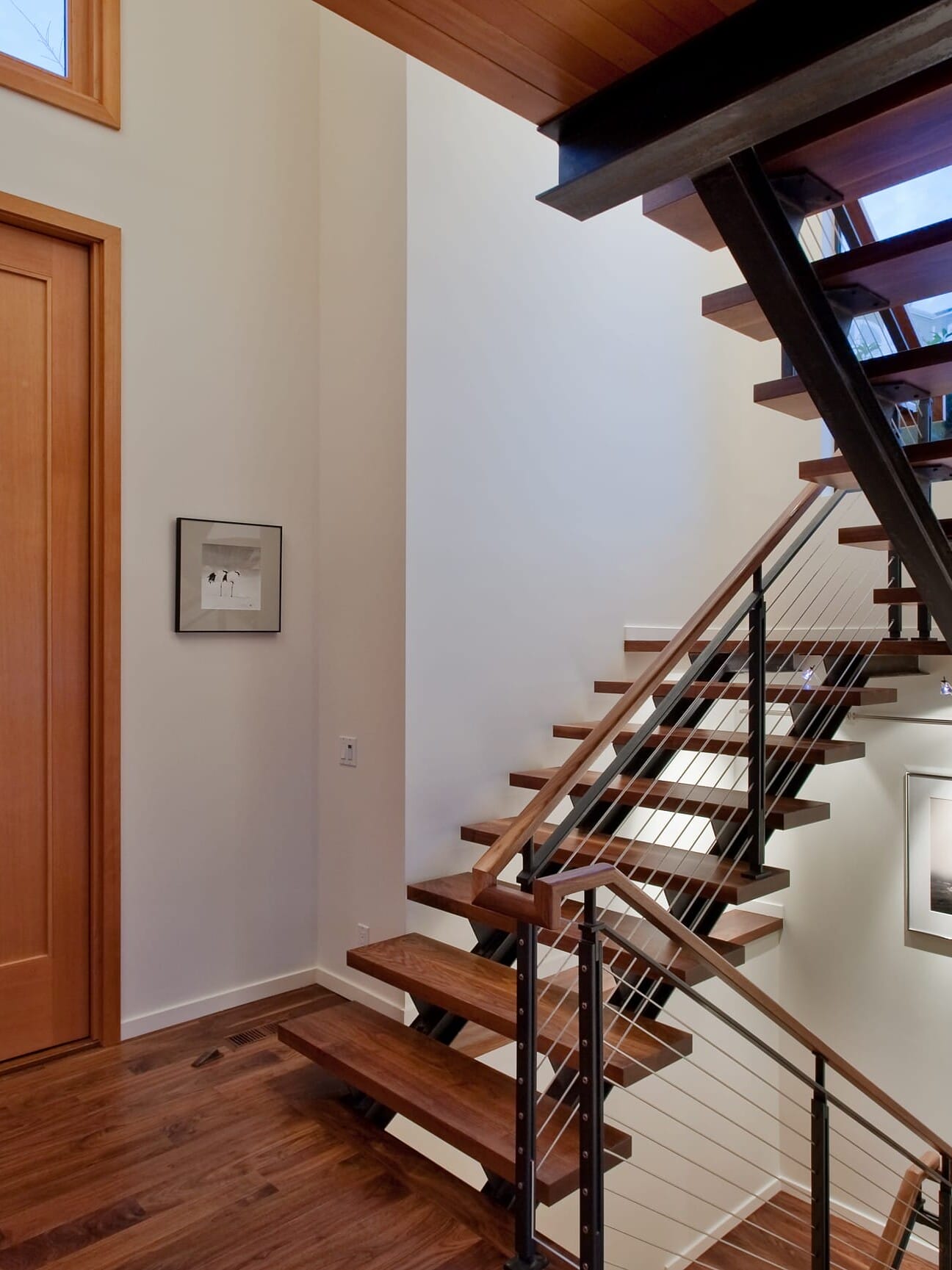 A modern staircase in a home with wooden railings.