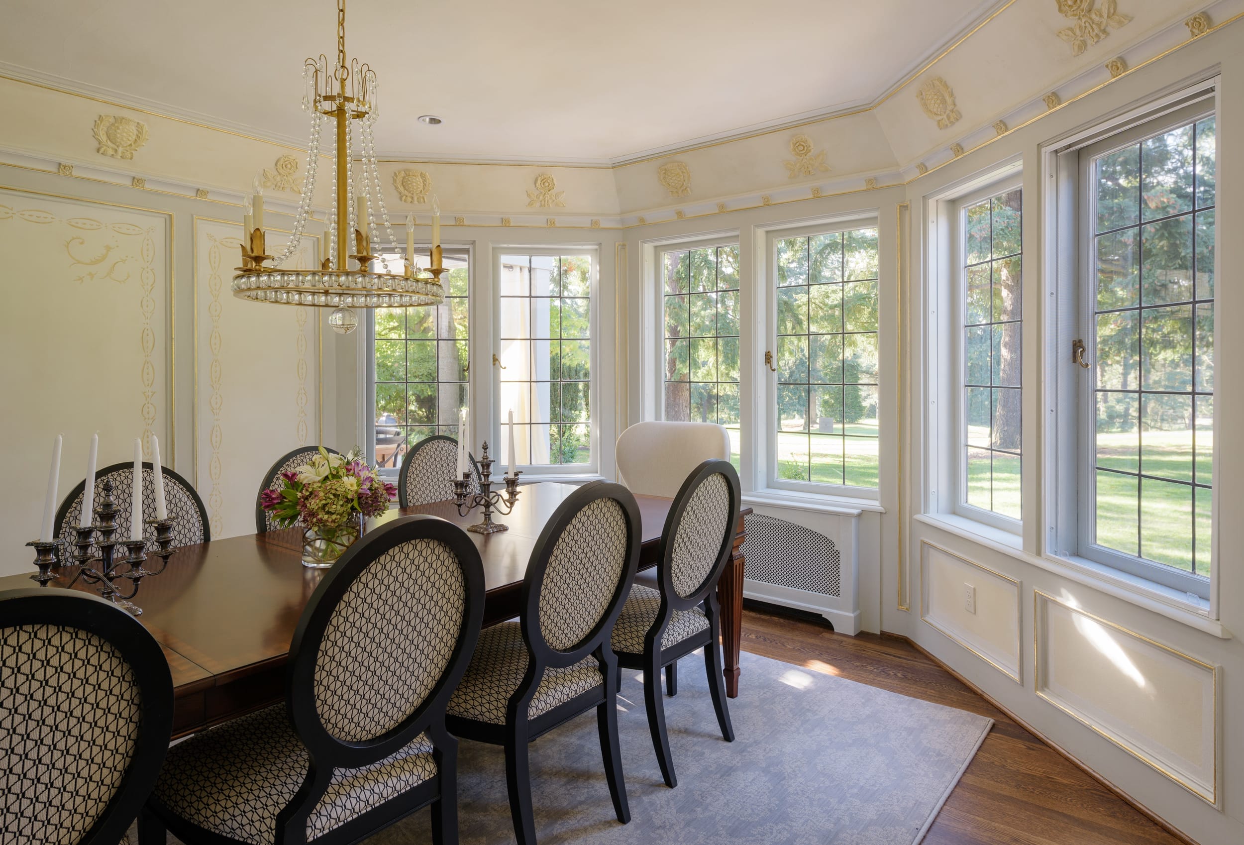 A dining room with large windows and a chandelier.