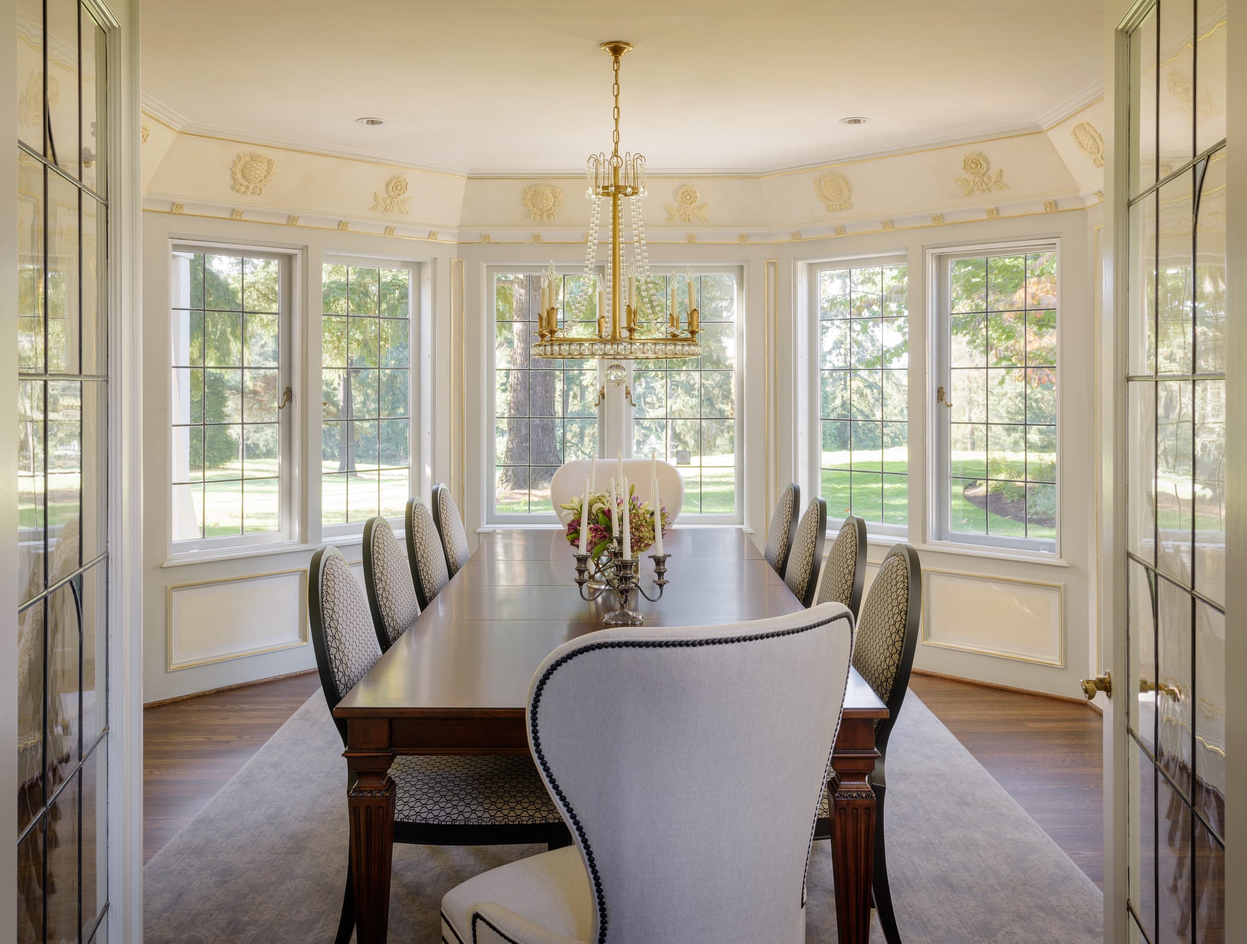 A dining room with a chandelier and chairs.
