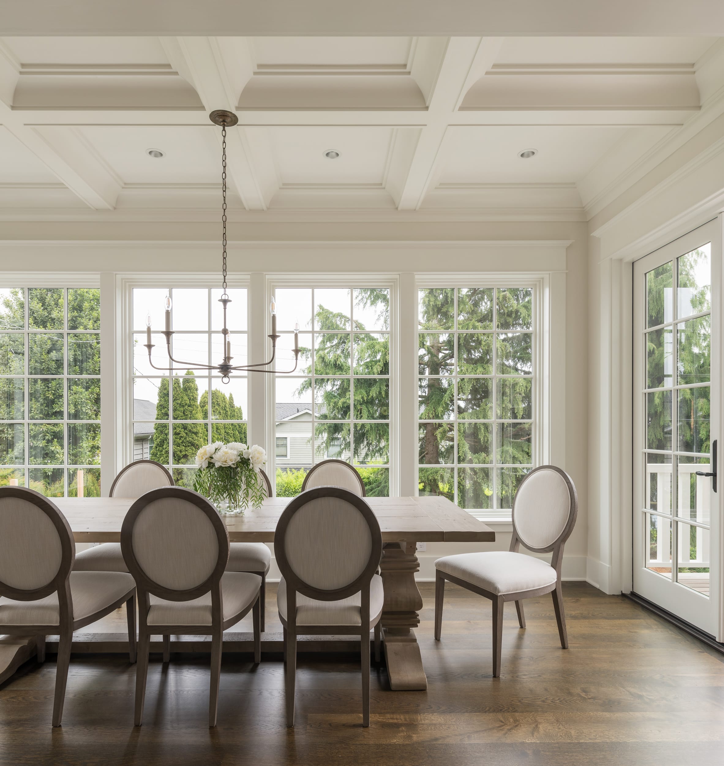A dining room in a modern home with hardwood floors and large windows, crafted by a skilled carpenter.