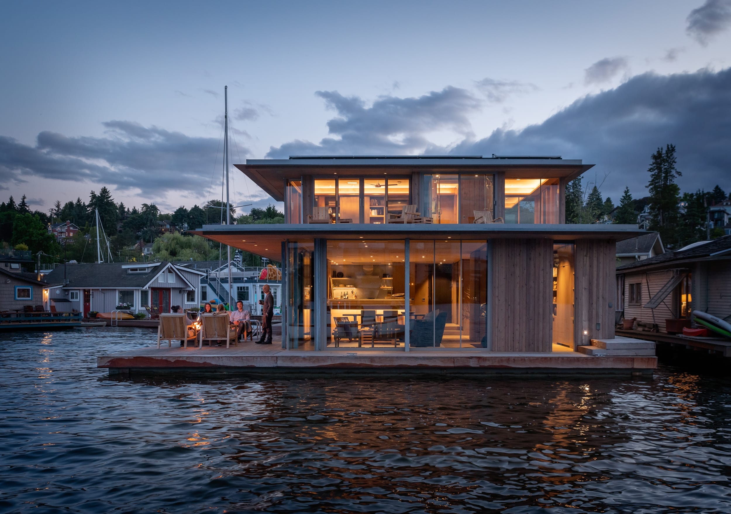 A floating home on the water at dusk, built by a skilled carpenter specializing in unique home building.