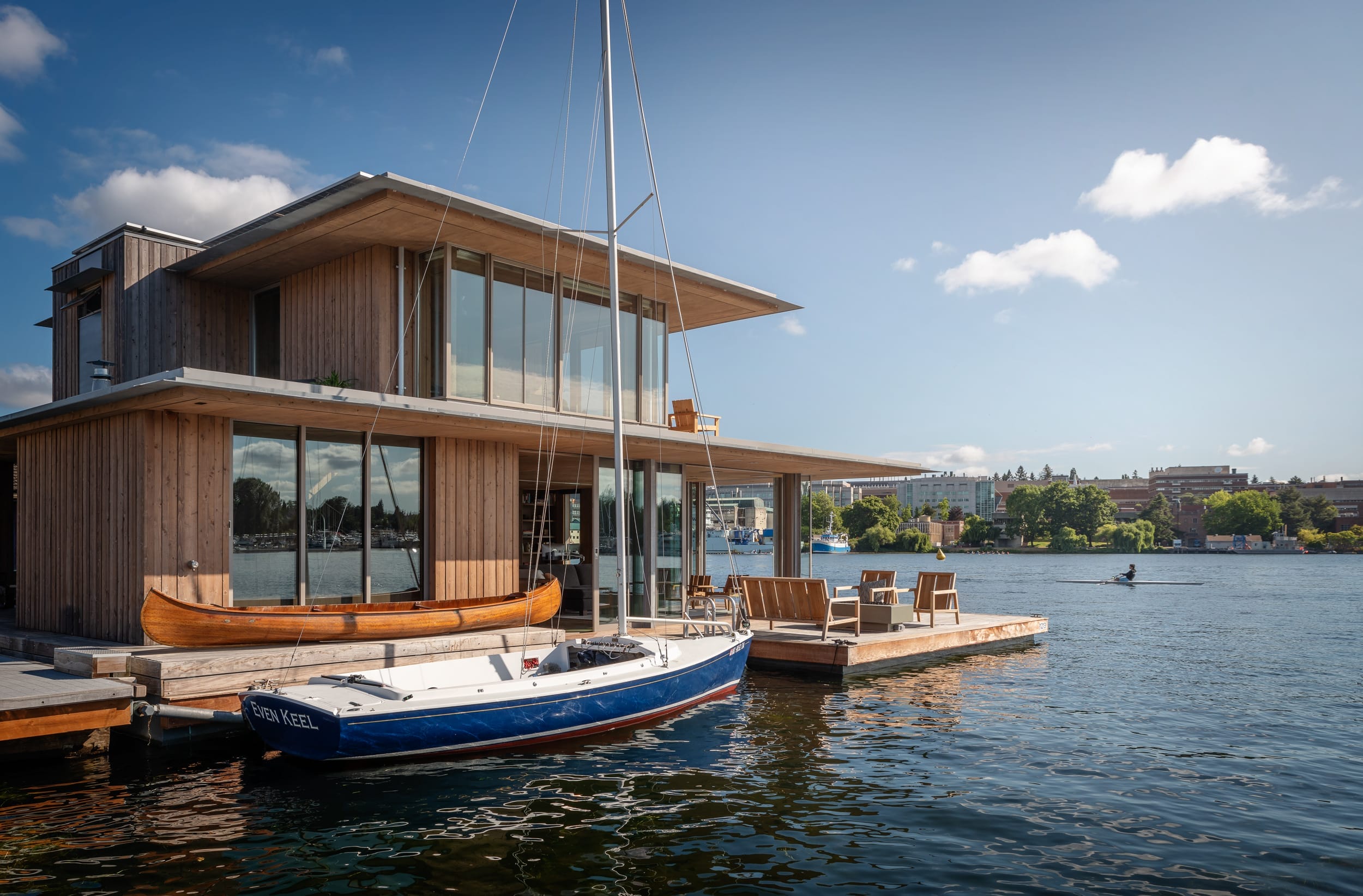 A modern floating home with a boat docked in the water.