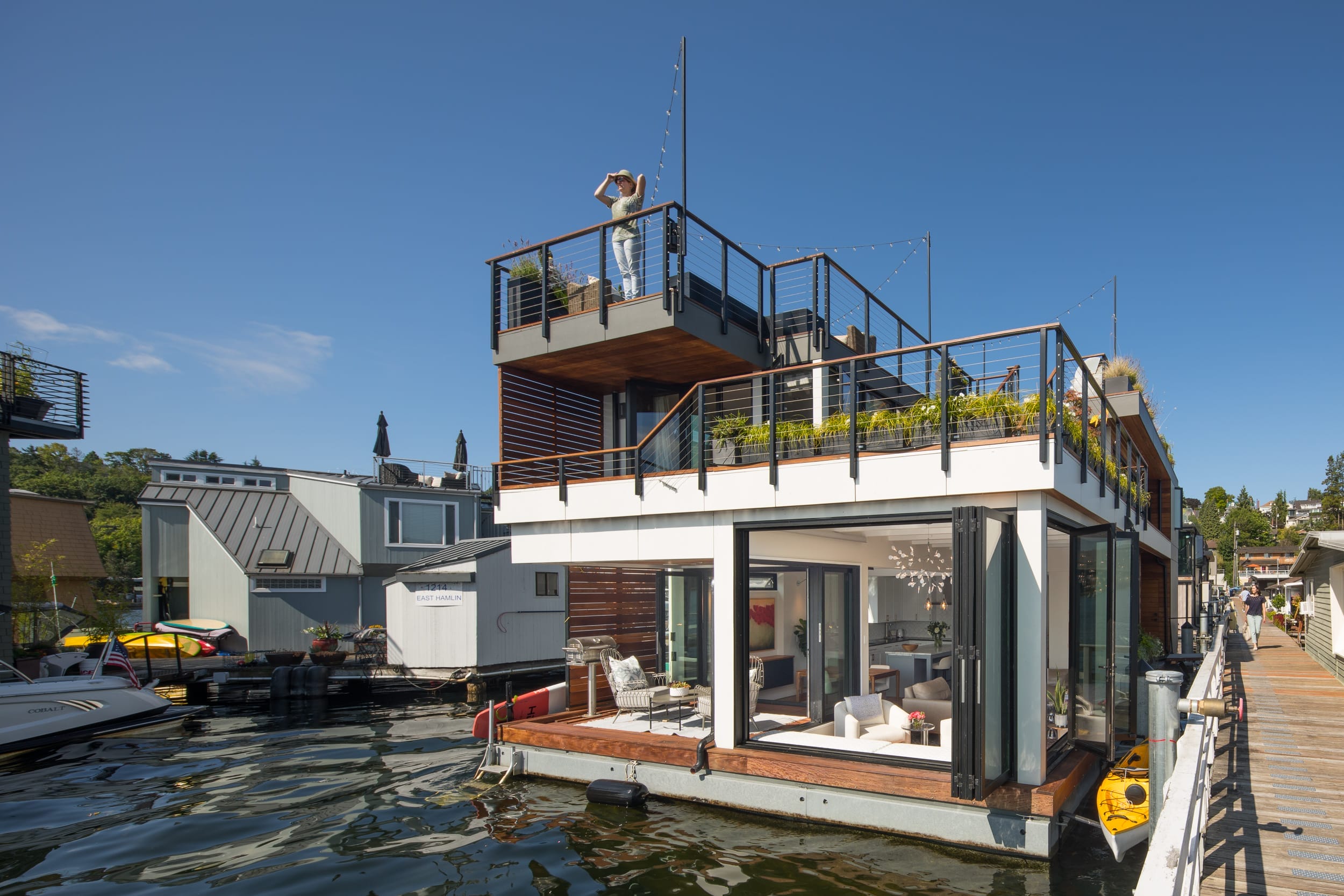 A carpenter-made modern houseboat is docked in a body of water.