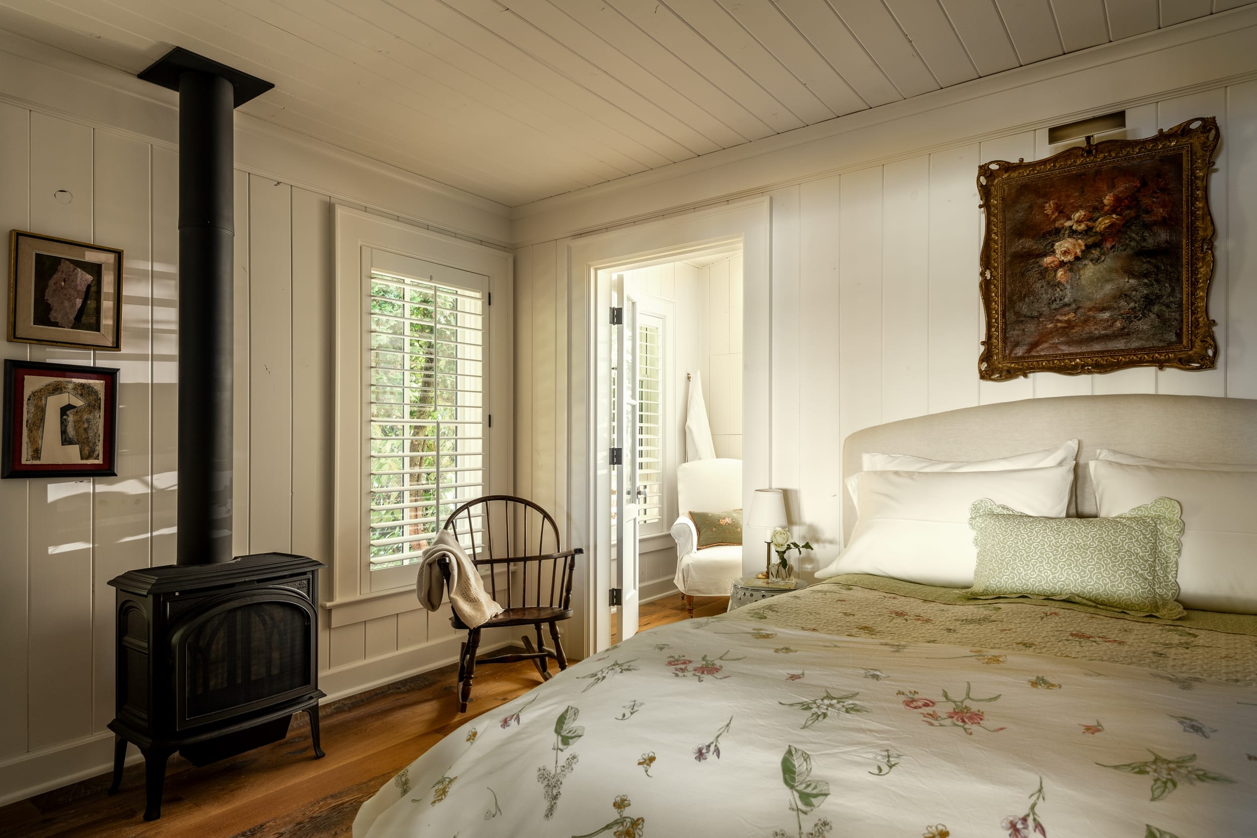 A white bedroom with a bed and a wood burning stove.