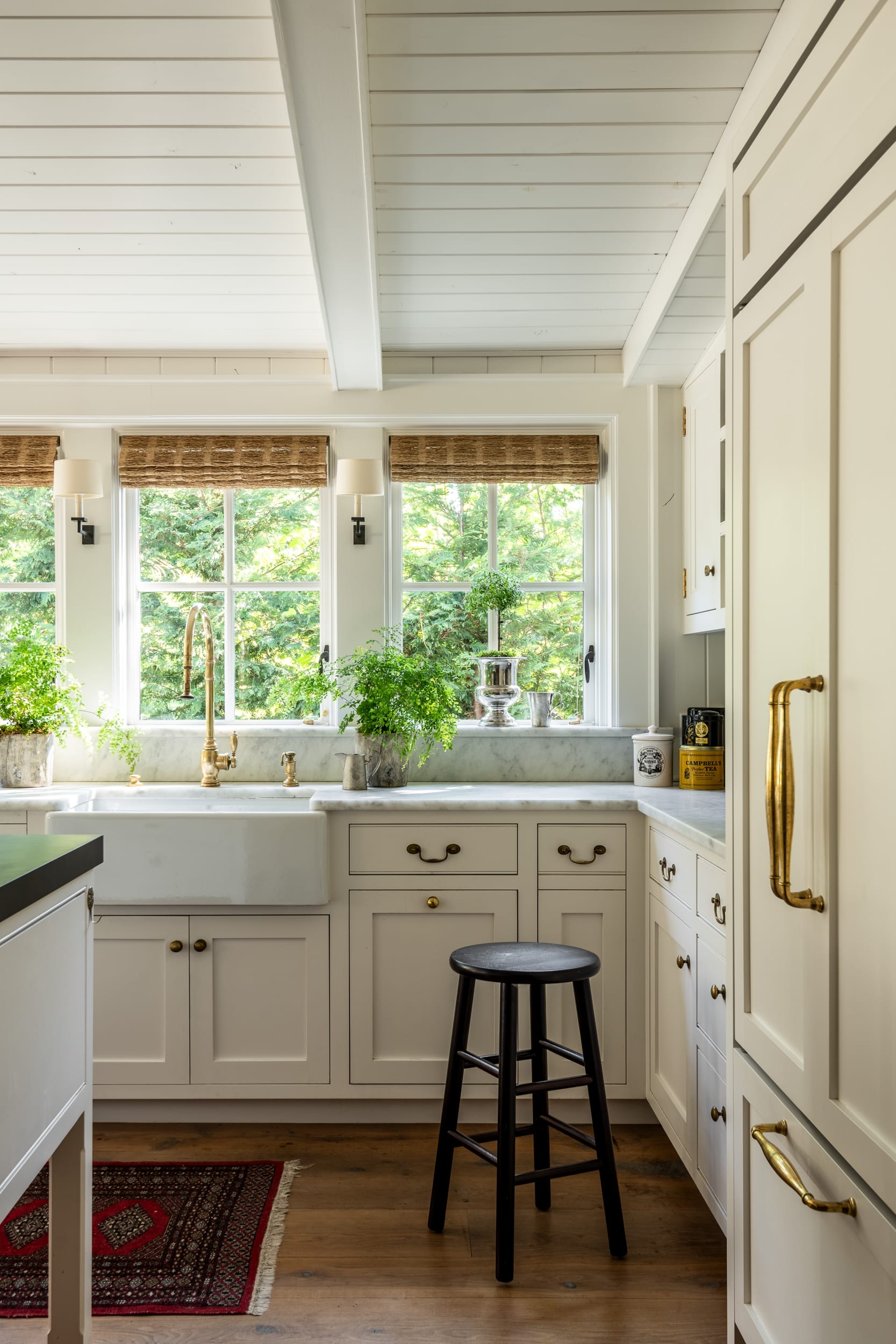 A white kitchen with a window and a stool.