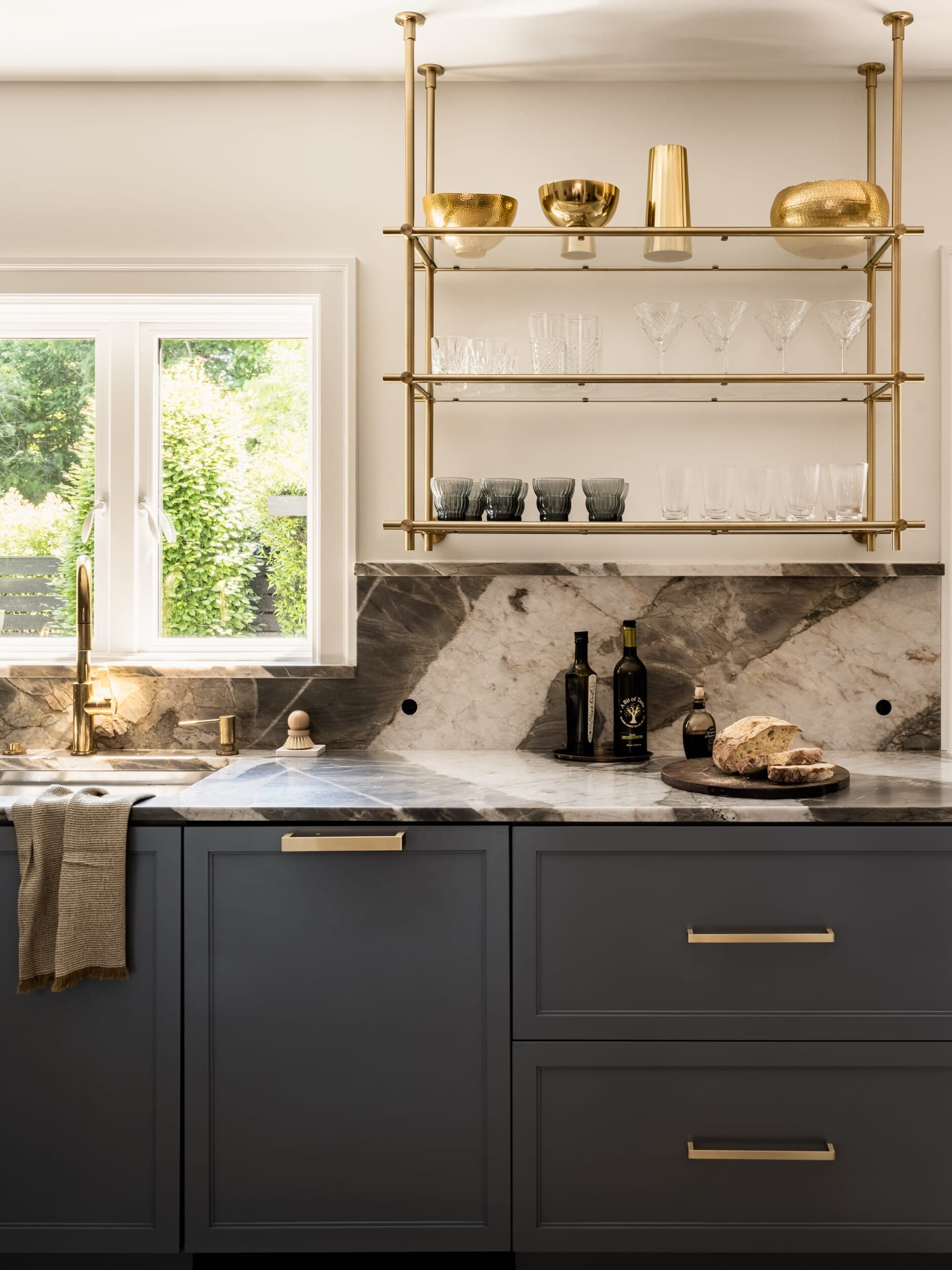 A black and gold kitchen with marble counter tops.