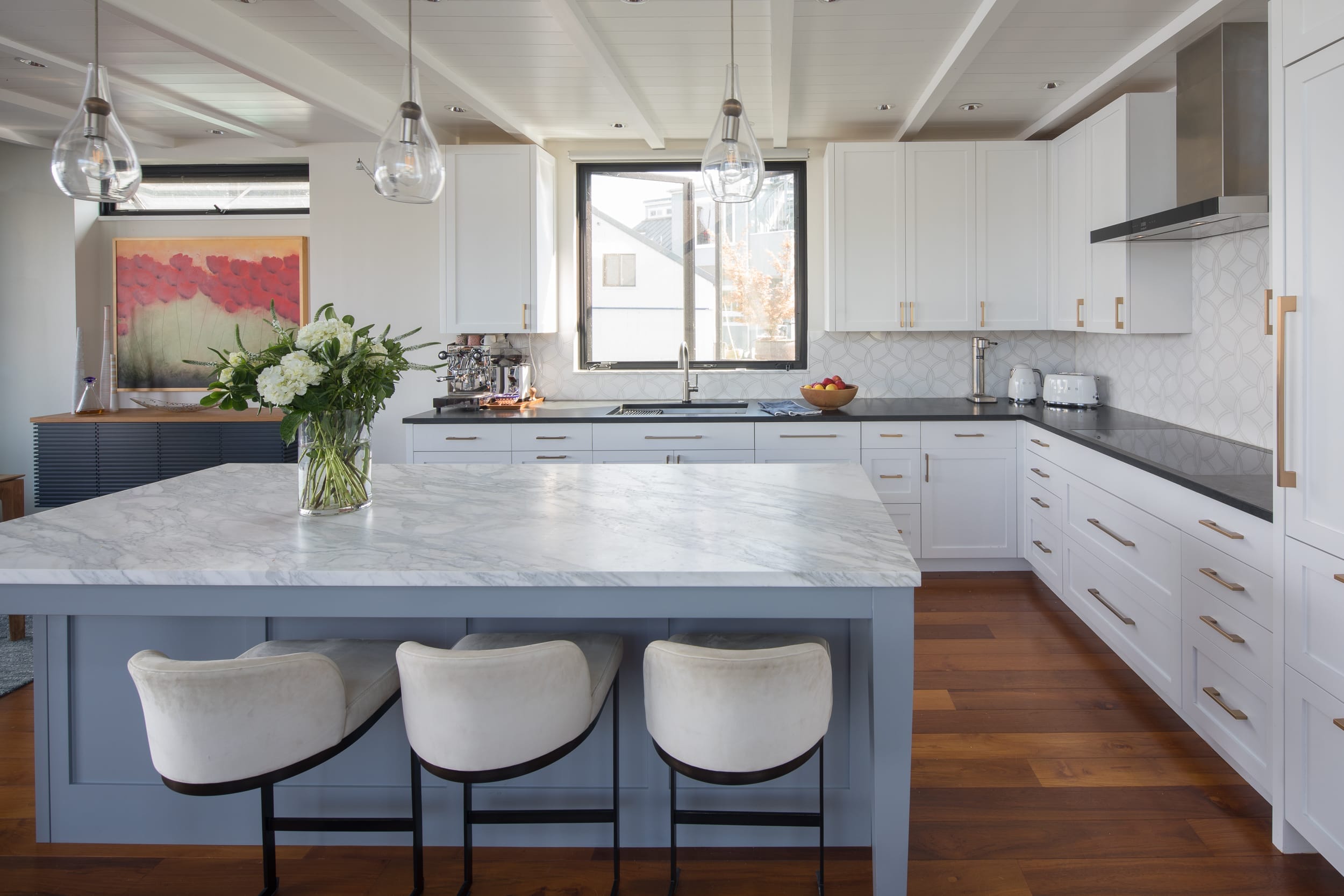 A modern white kitchen with marble counter tops and stools, perfect for a floating home.