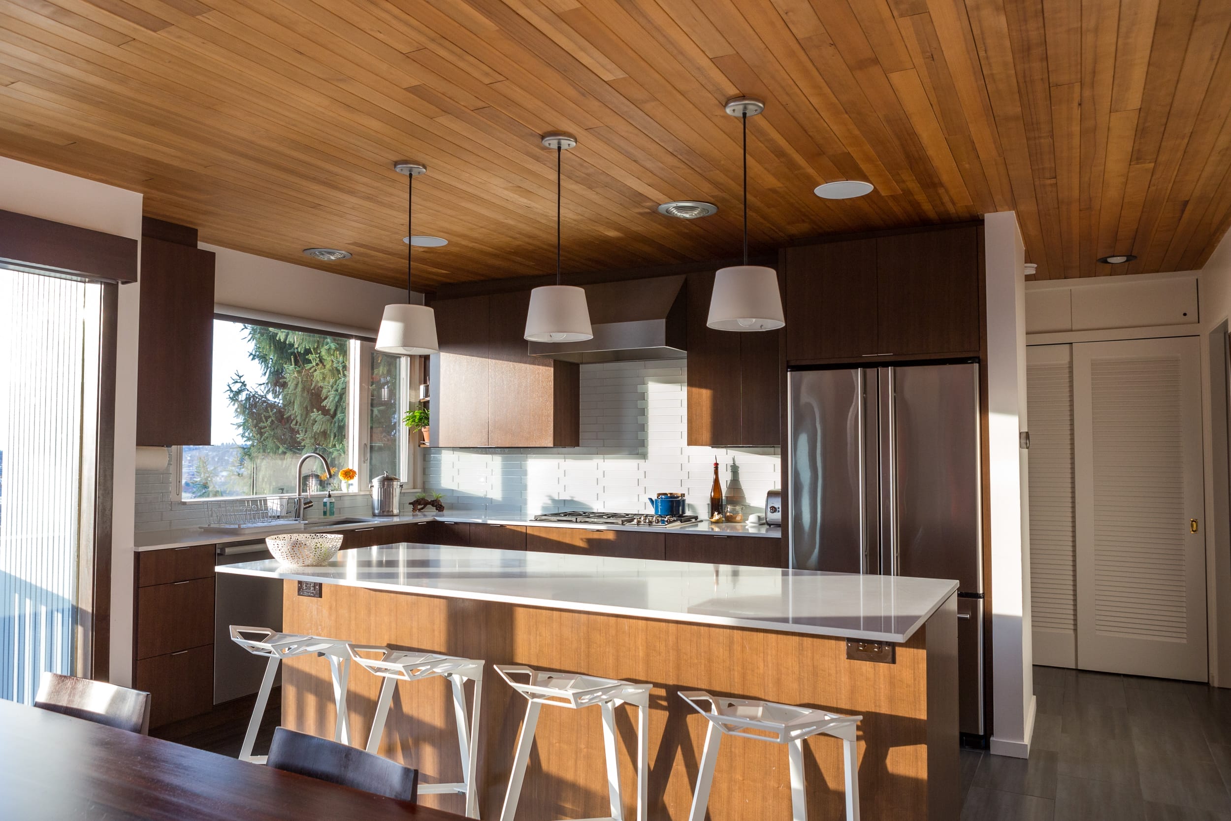 A modern kitchen with a wooden ceiling.