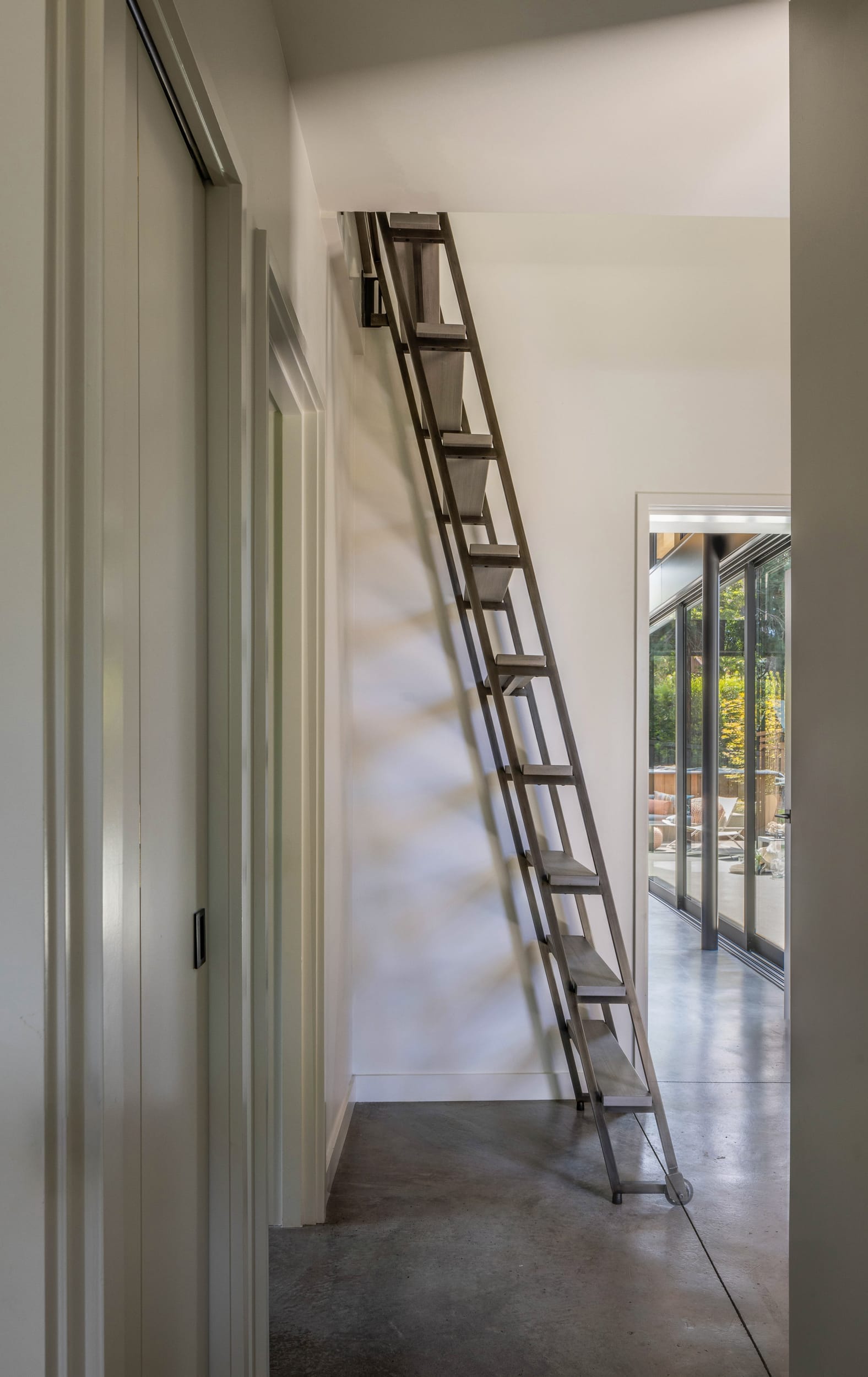 A modern home with a ladder leading up to a door.