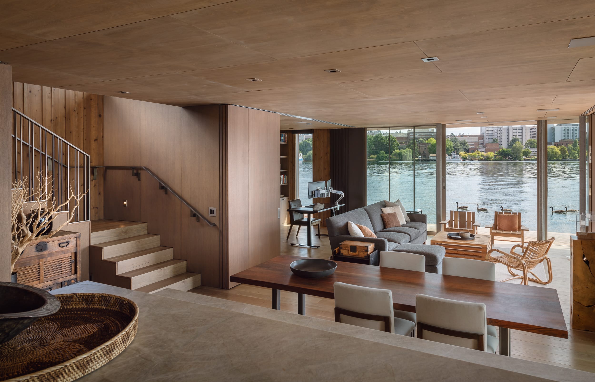 A modern living room with stairs and a view of the river, designed by a carpenter.