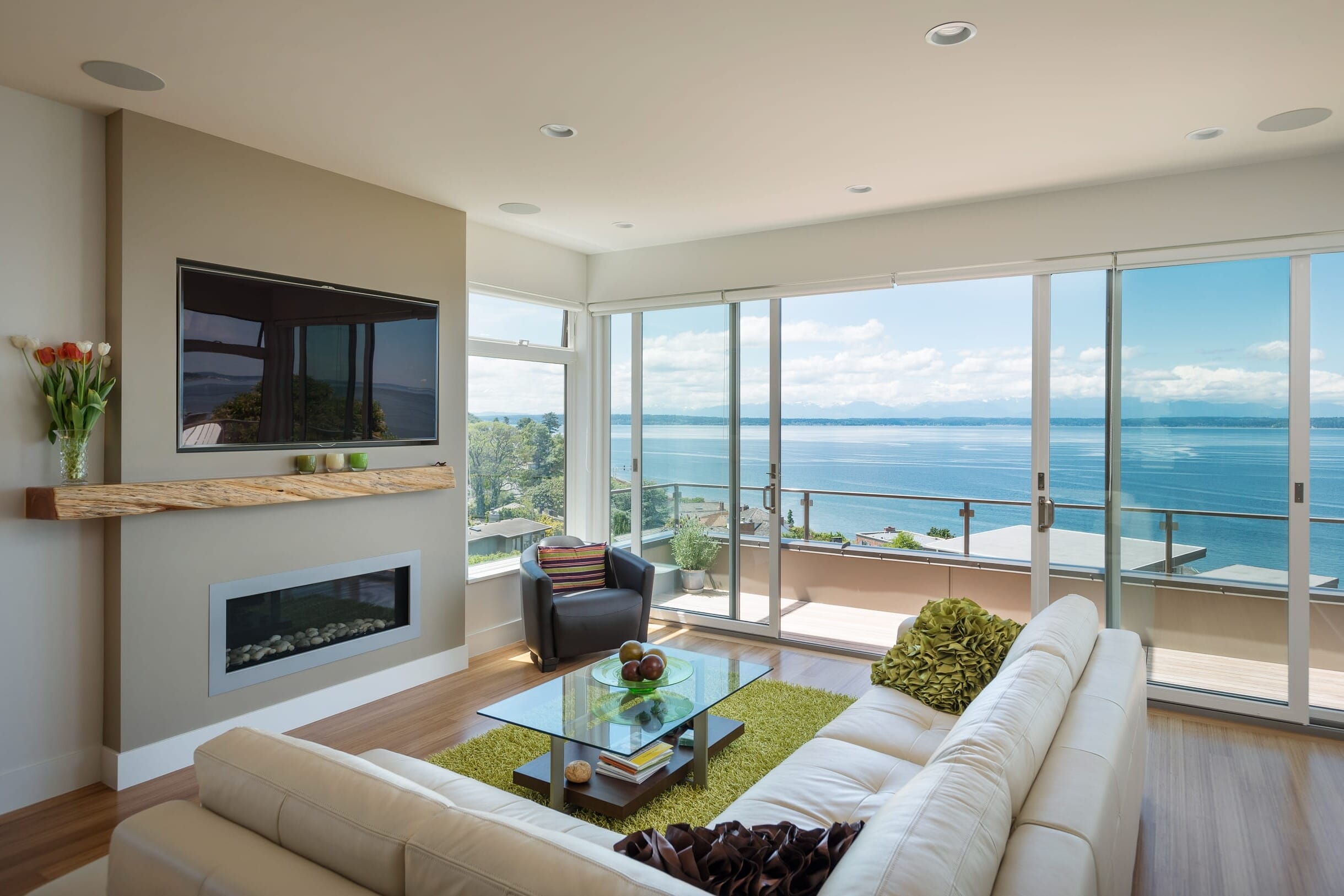 A living room with a large glass door overlooking the water.