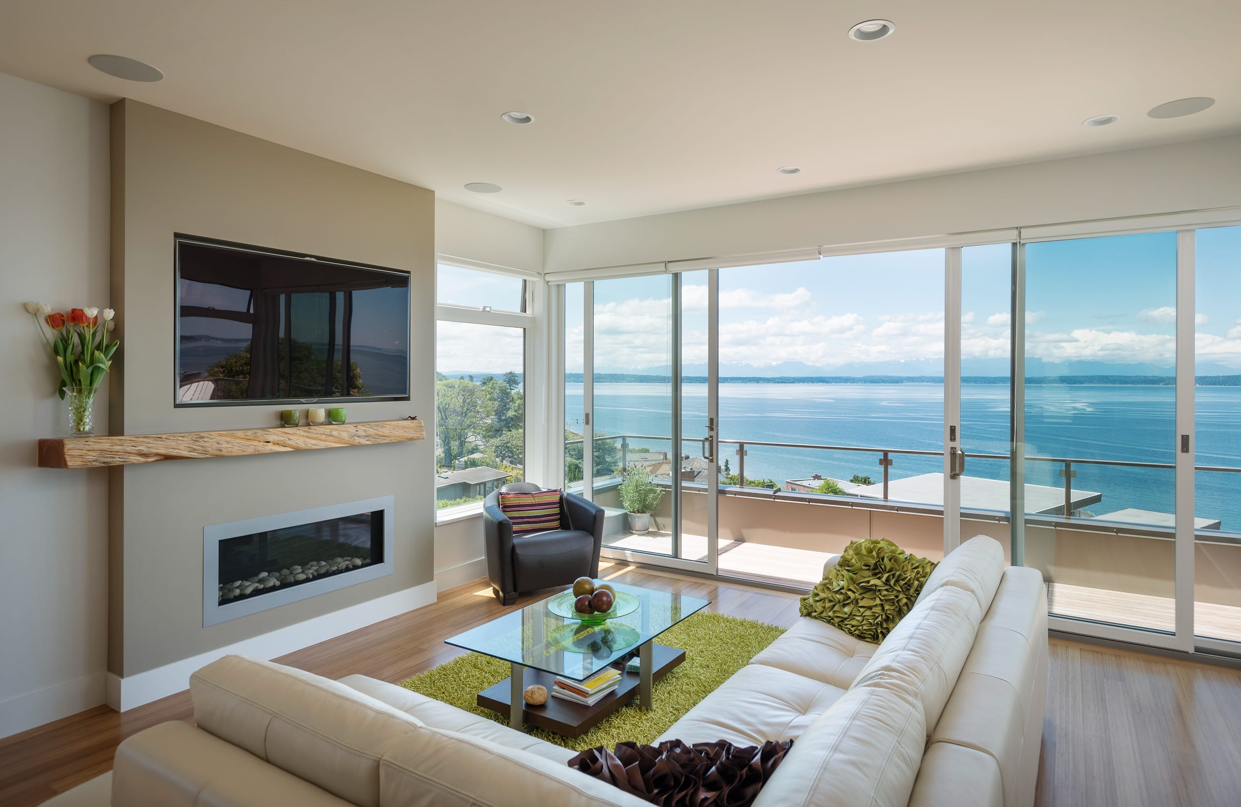 A living room with a large glass door overlooking the water.
