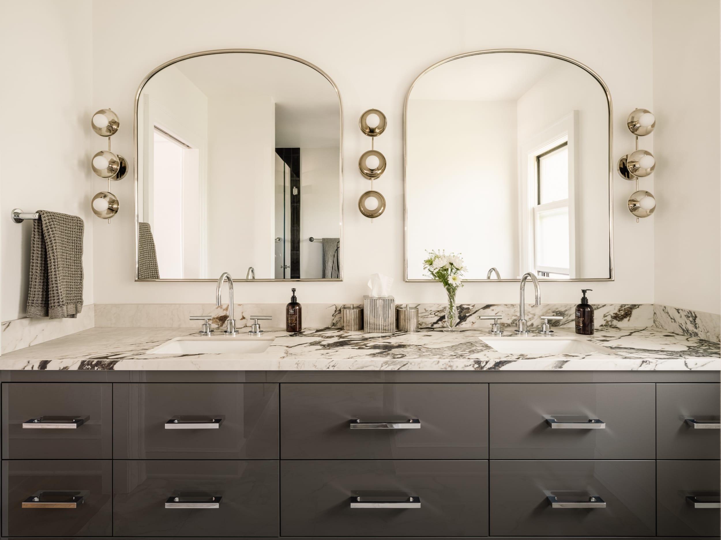 A bathroom with marble counter tops and two mirrors.