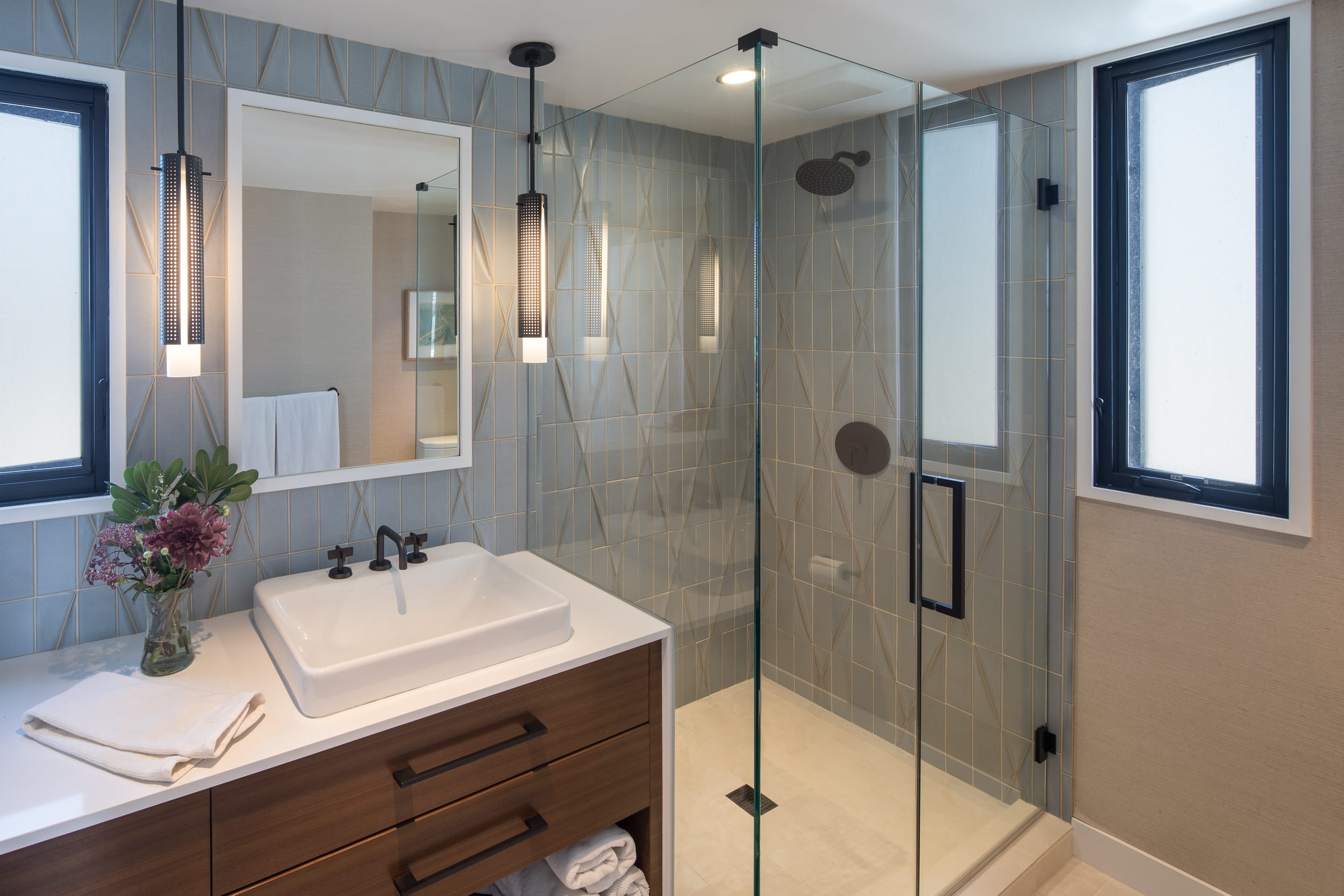 A modern home bathroom featuring a glass shower stall and sink.