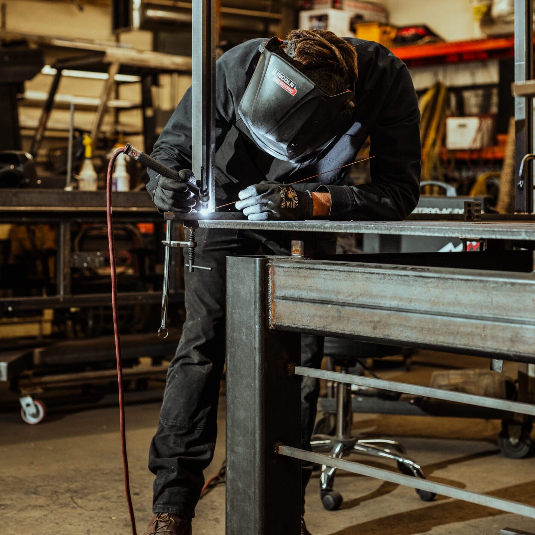 In the Dyna Metal Shop Seattle, a man skillfully welds a piece of metal.