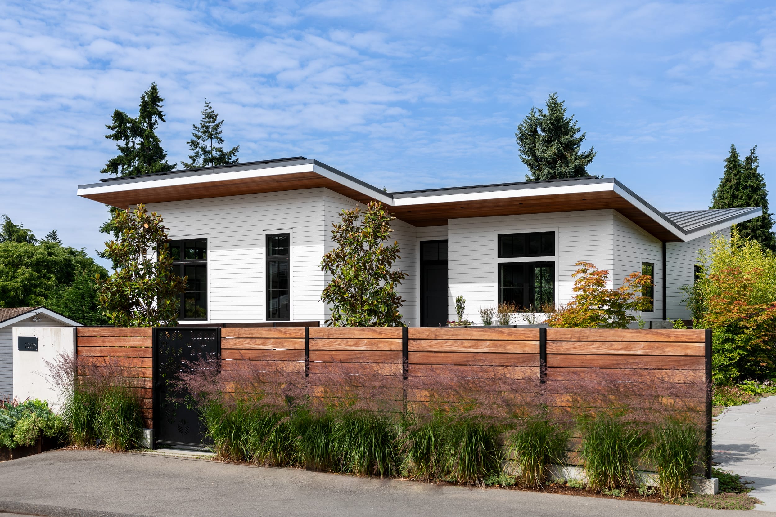 A modern home with a wooden fence and bushes.