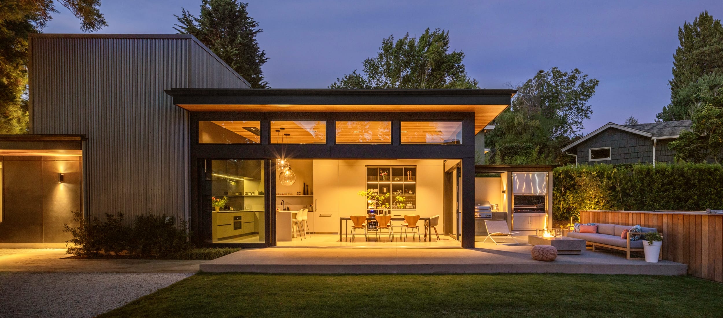A modern home with a large patio and floating home design at dusk.