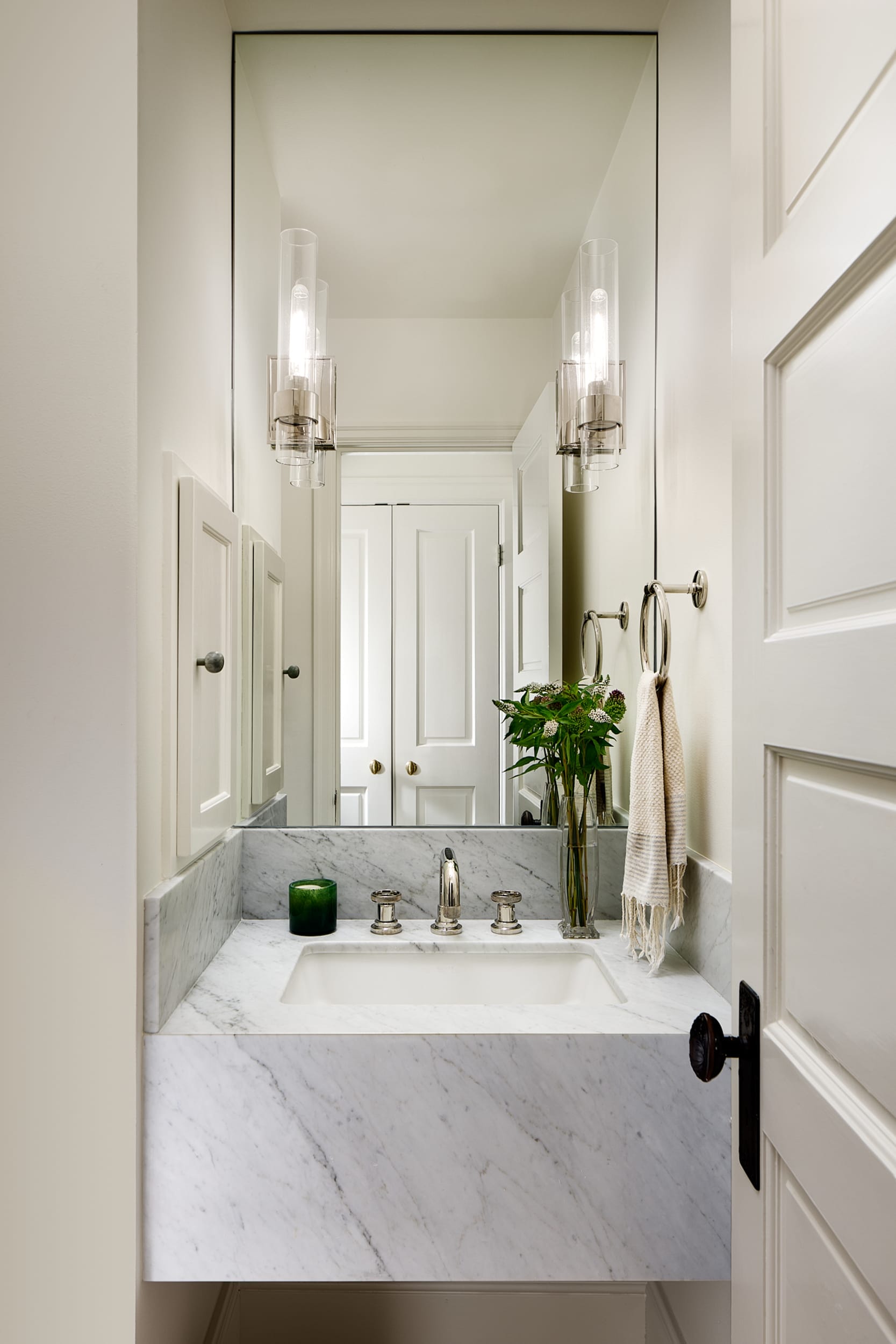 A white bathroom with a marble sink and mirror in a home building project.
