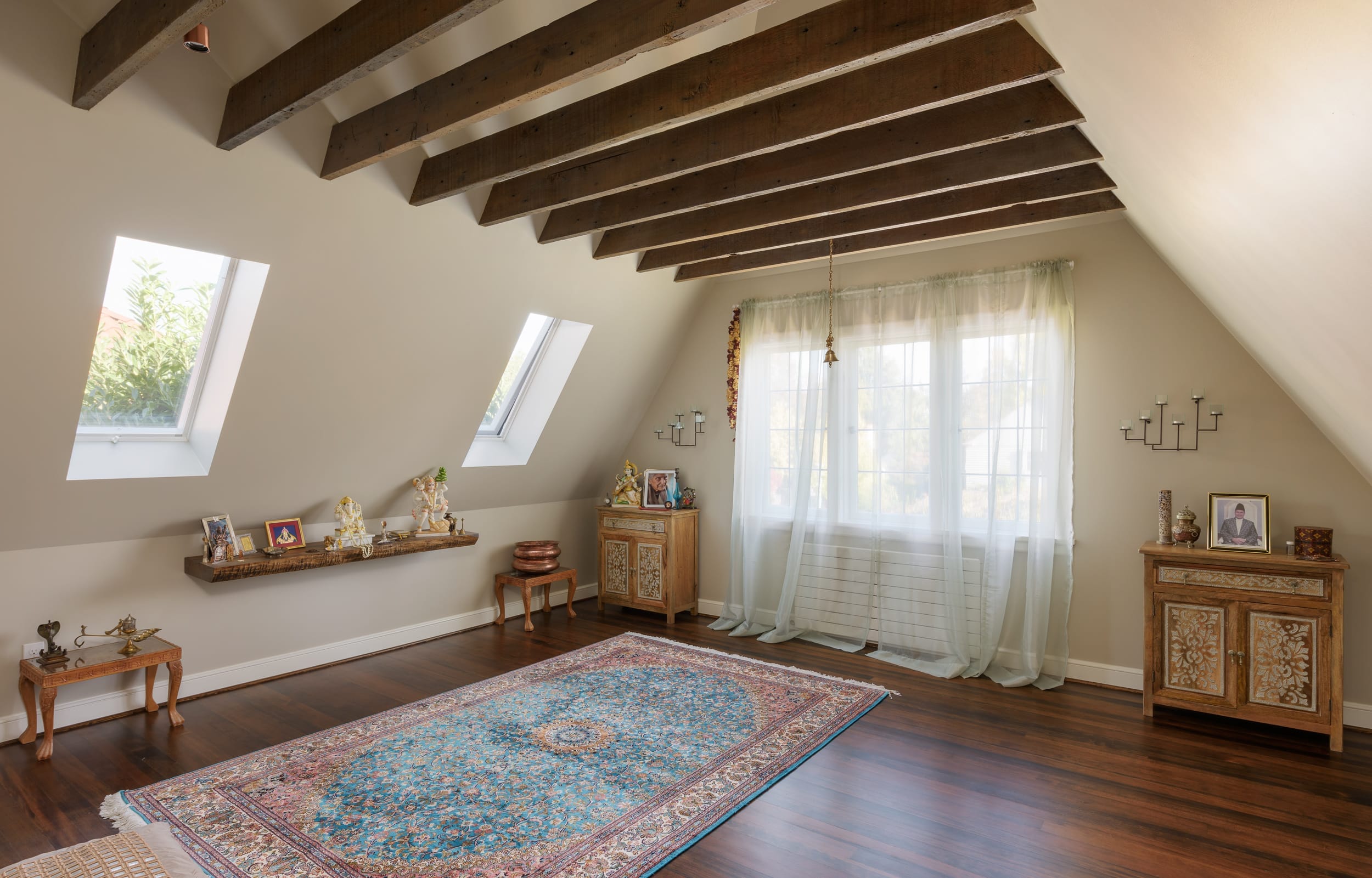 An attic room with wooden beams and a rug.