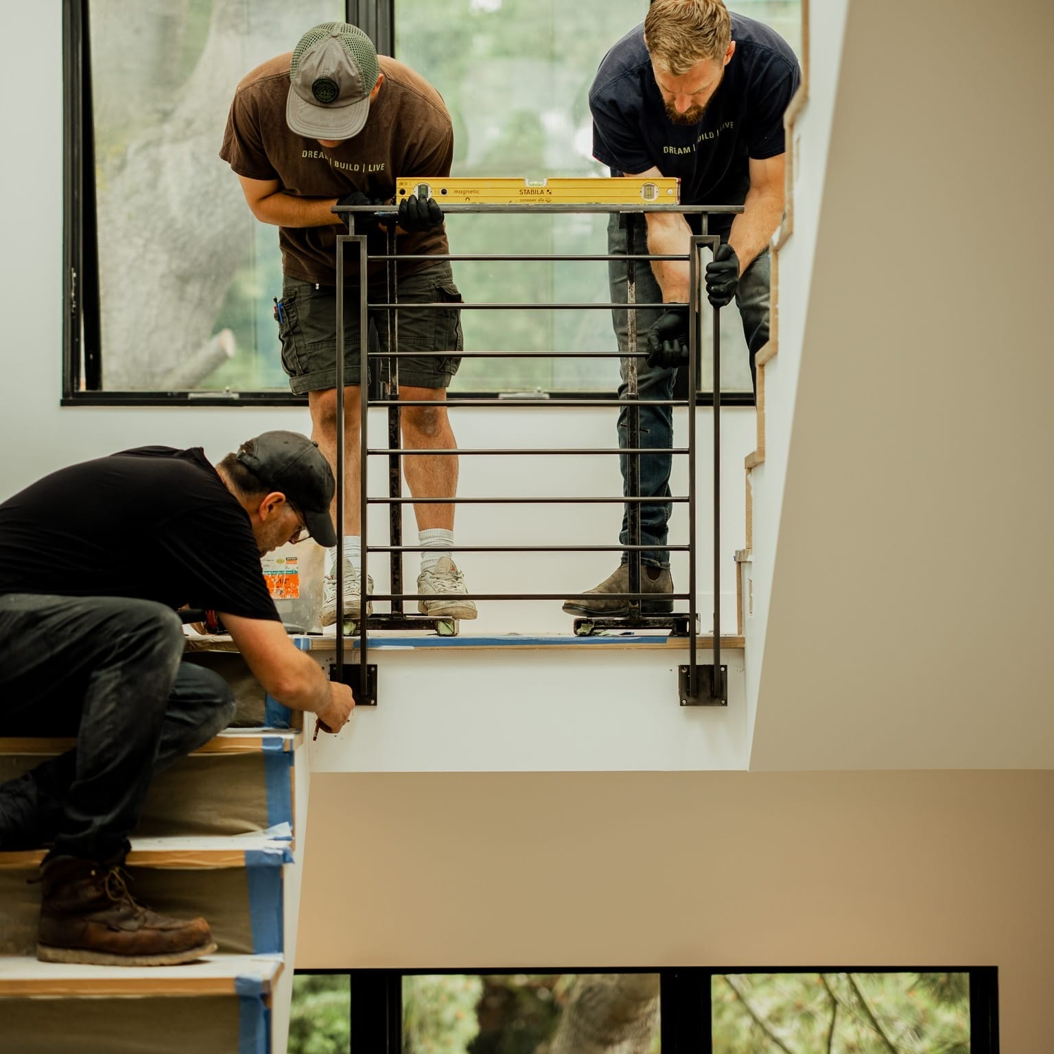 Three men from Dyna Builders Metal Shop working on a staircase in a home.