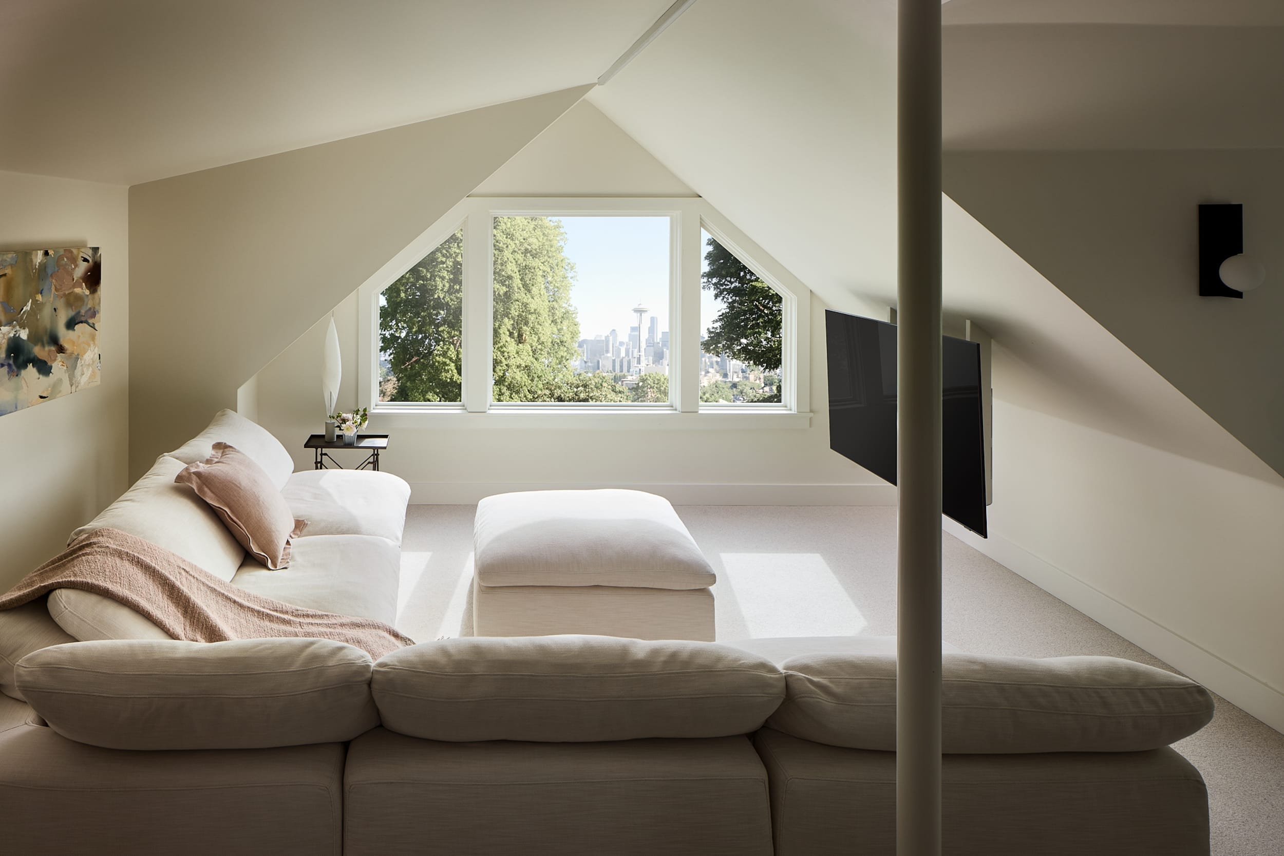 A modern home with a white couch in an attic, offering a stunning view of the city.